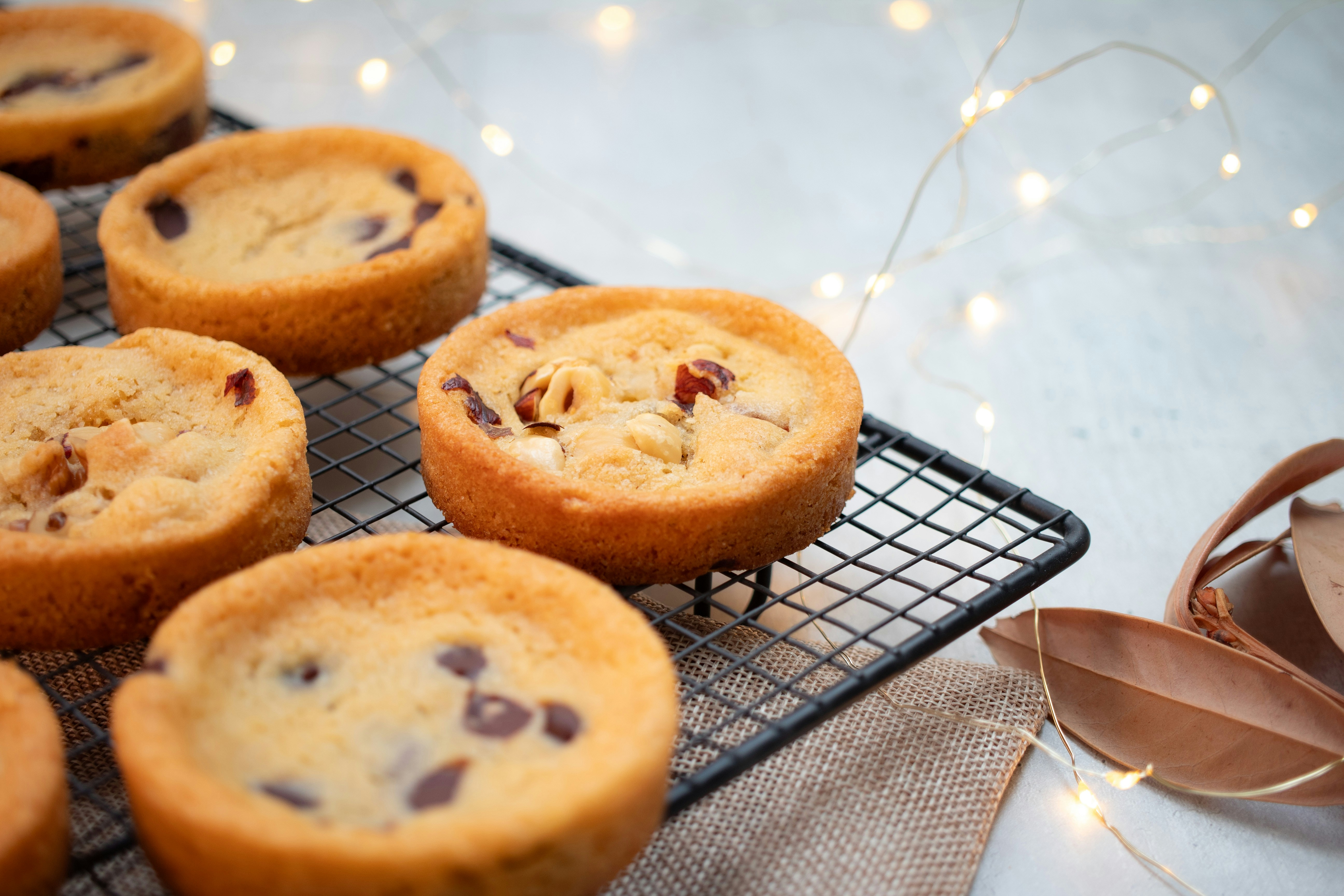 Round cookies with chocolate chips and nuts on a black wire cooling rack
