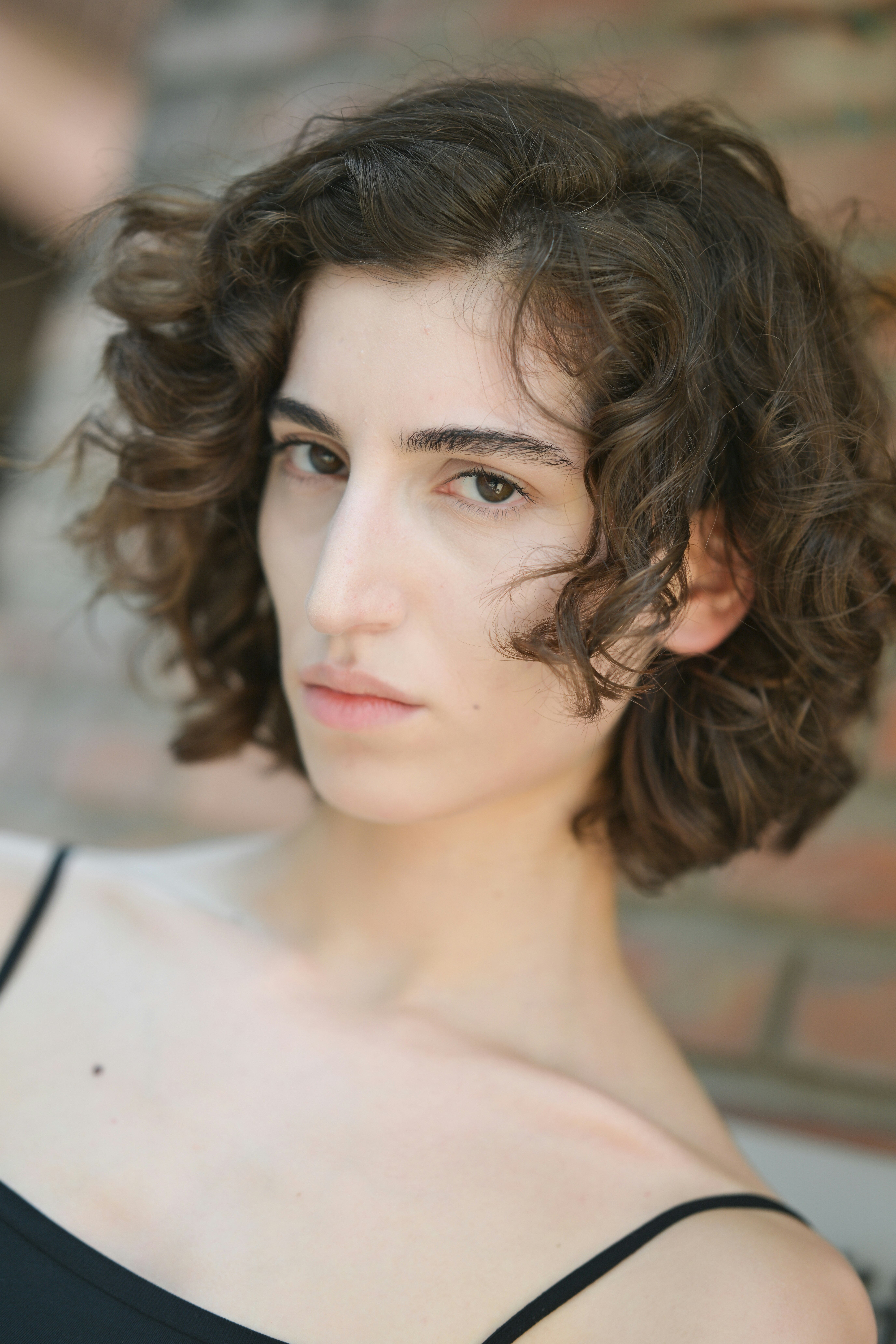 A woman with short curly brown hair wearing a black top