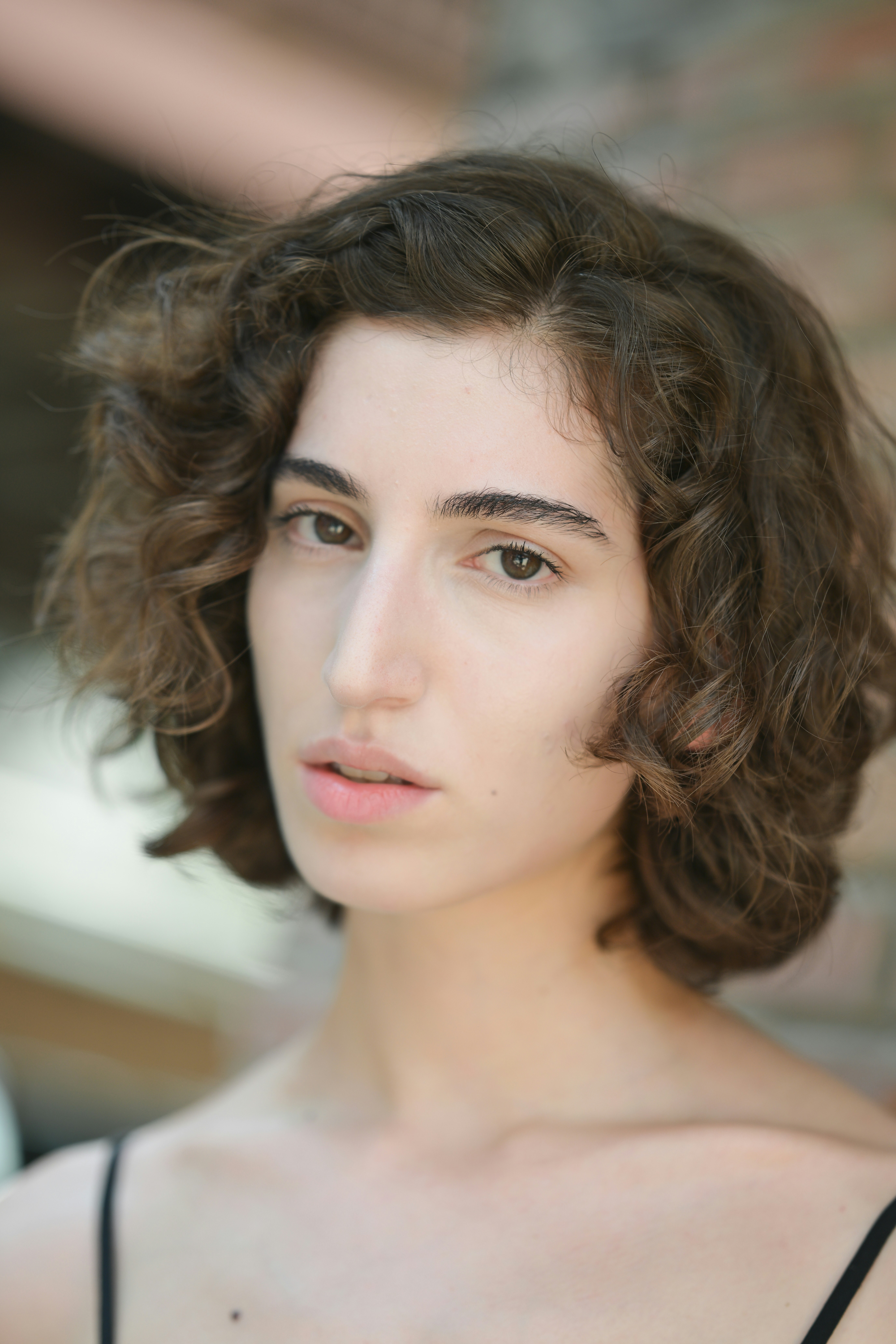 A woman with short curly brown hair looking directly at the camera
