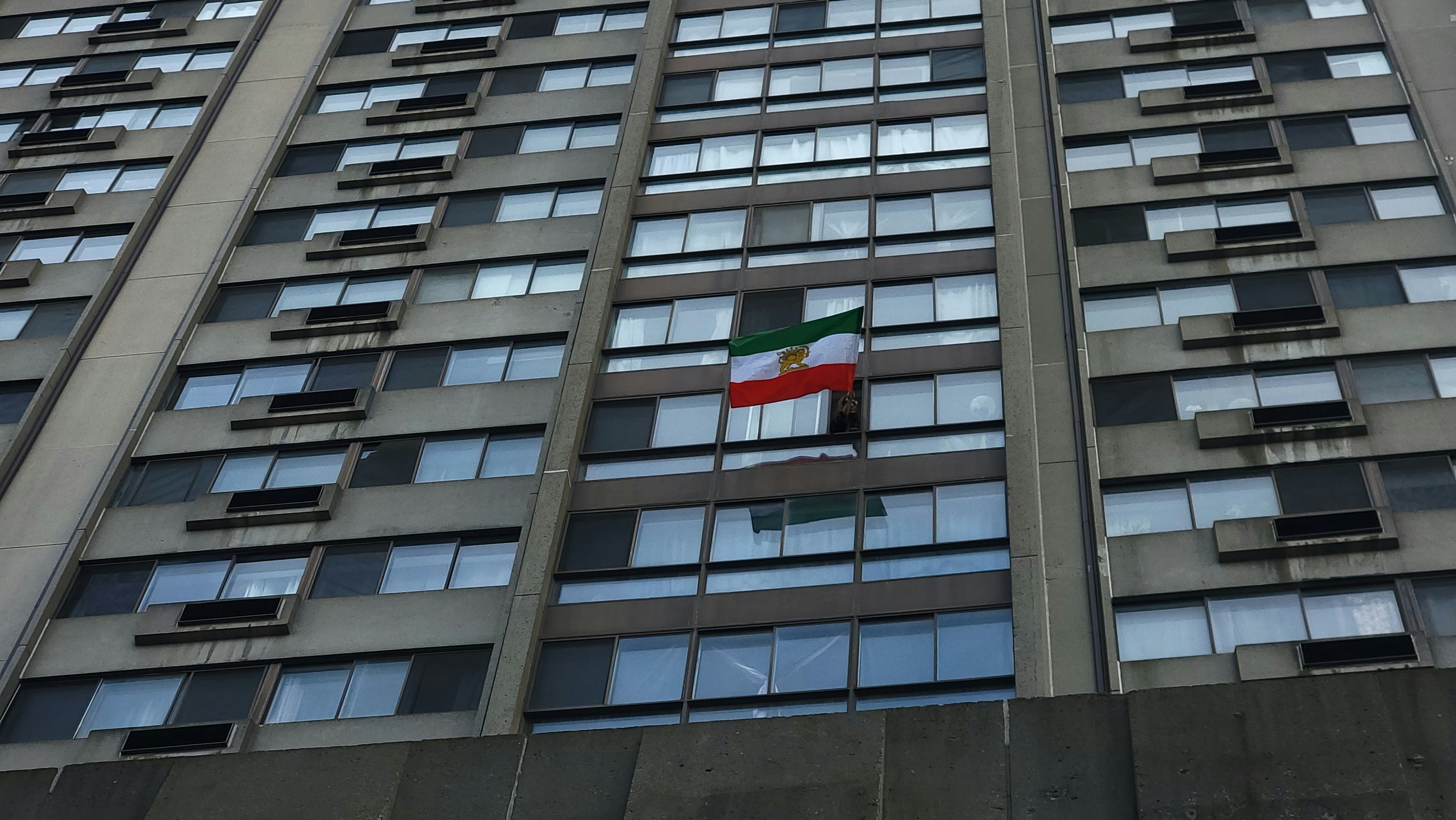 Un drapeau iranien suspendu à la fenêtre d’un grand immeuble en béton