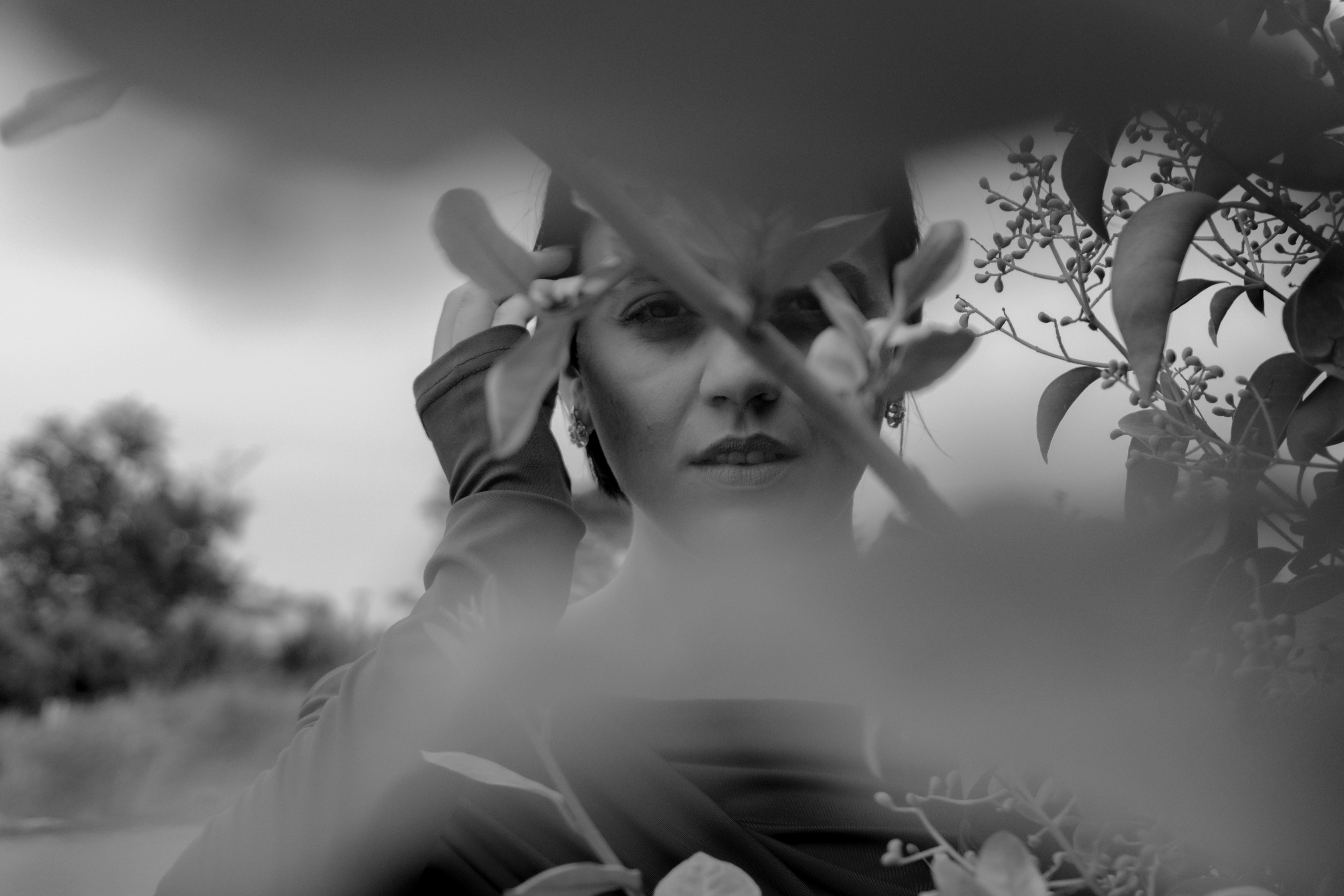 A woman seen through foliage in a black and white portrait