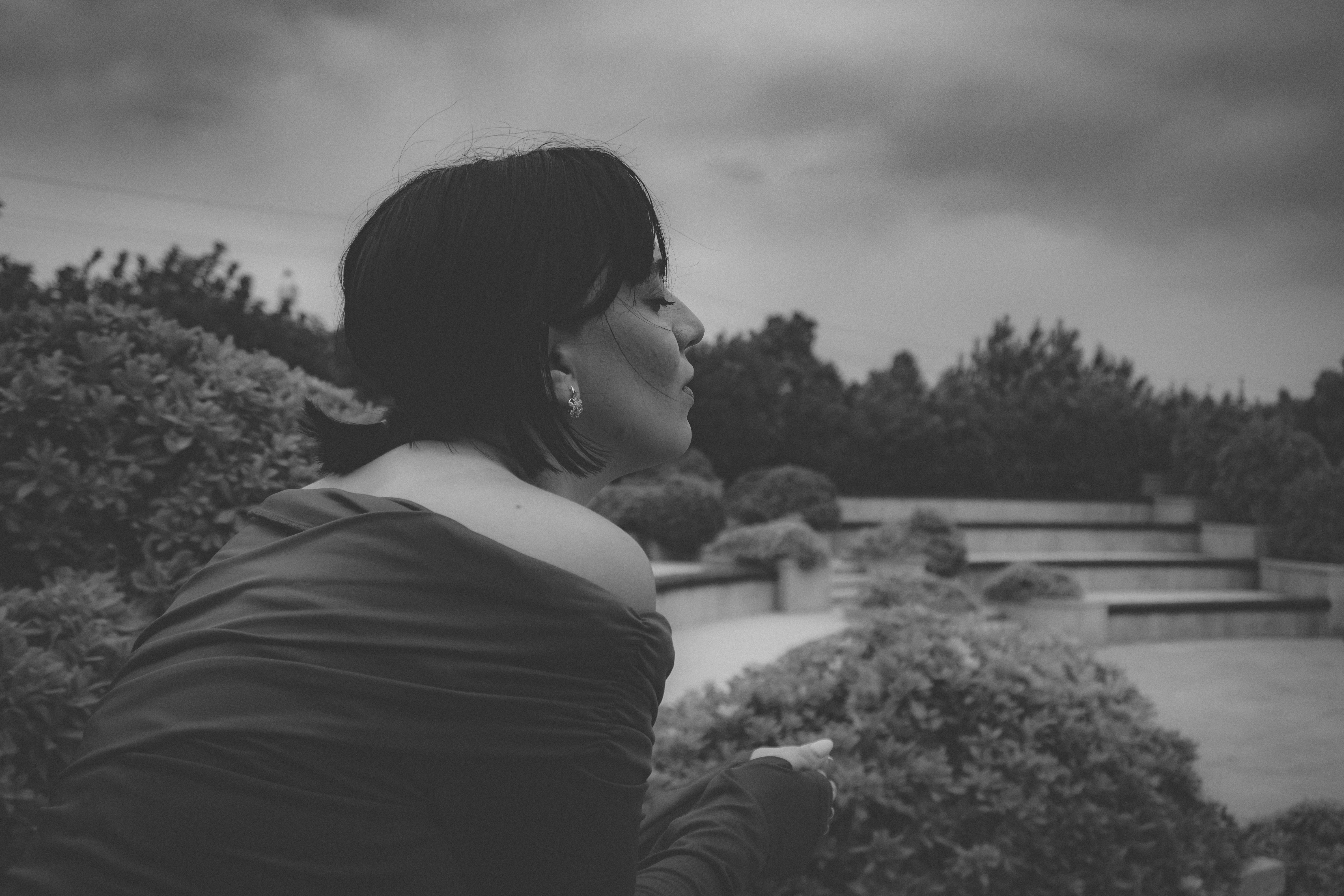 A woman in an off-the-shoulder top looking away in a garden
