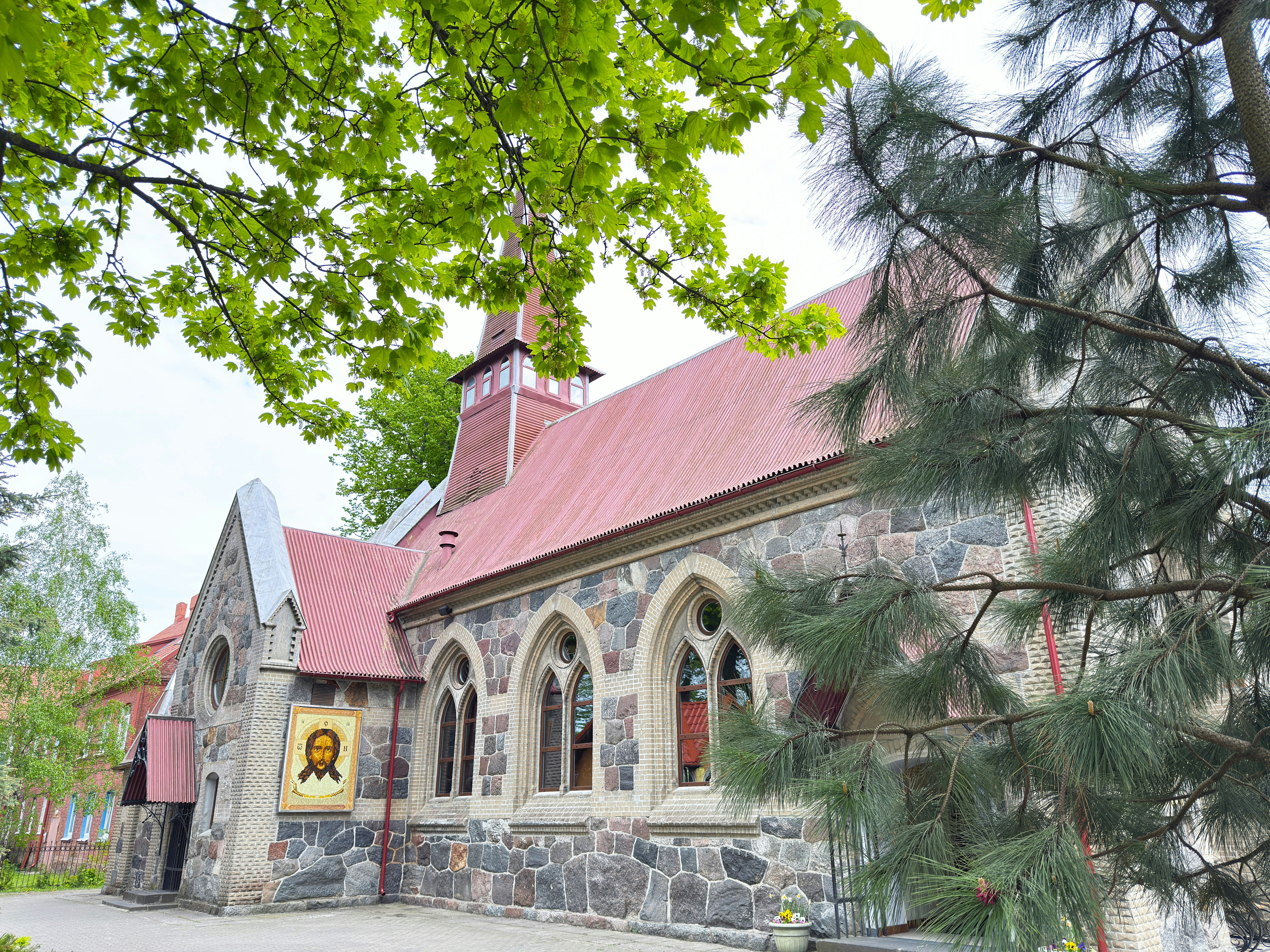 A stone church with a red roof and an icon of Jesus on the wall