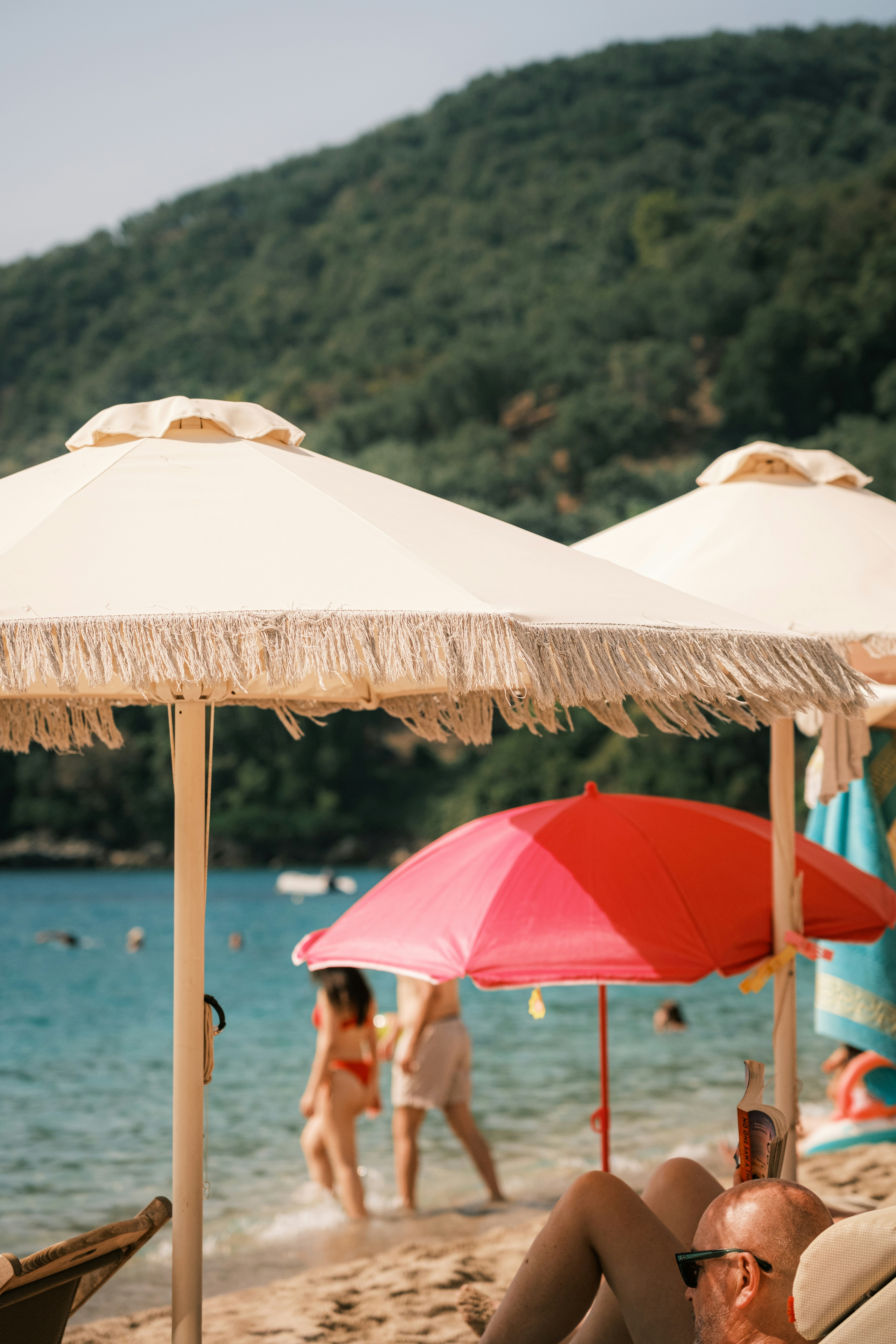 Beach umbrellas with fringe on a sandy shore with people in the background