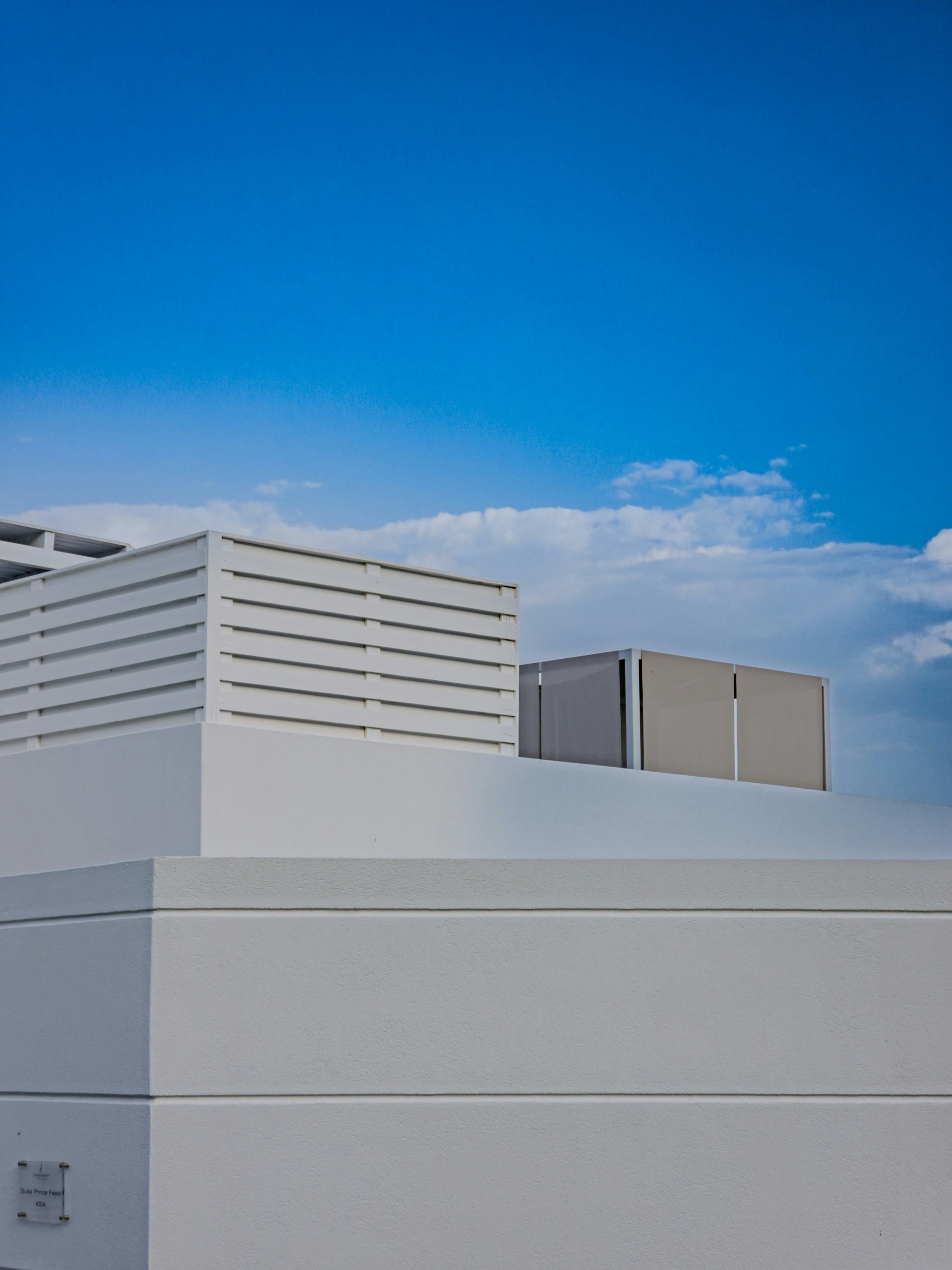 White architectural roof structures with slats against a clear blue sky