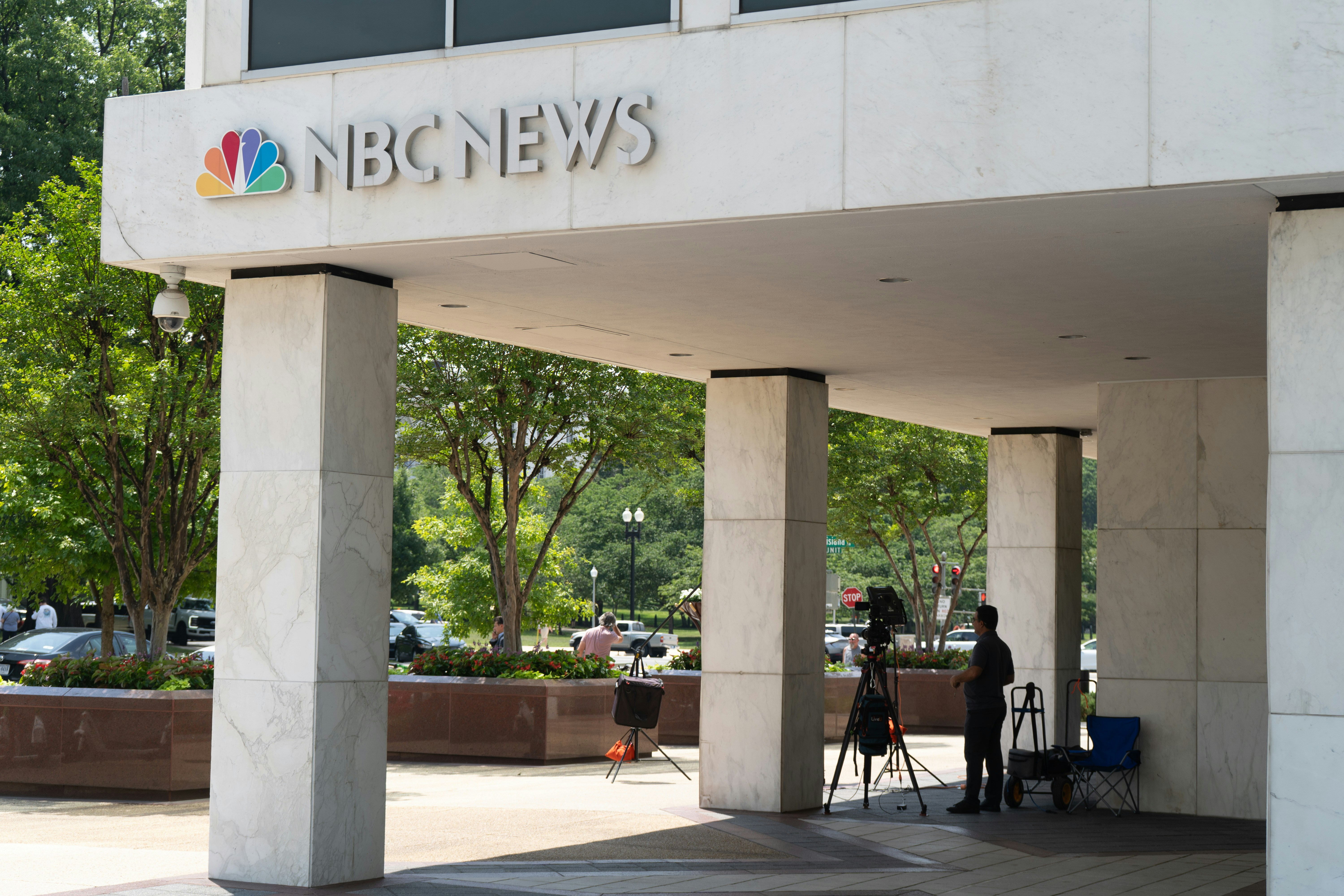 Eine Person, die eine Kamera auf einem Stativ vor dem NBC-News-Gebäude bedient