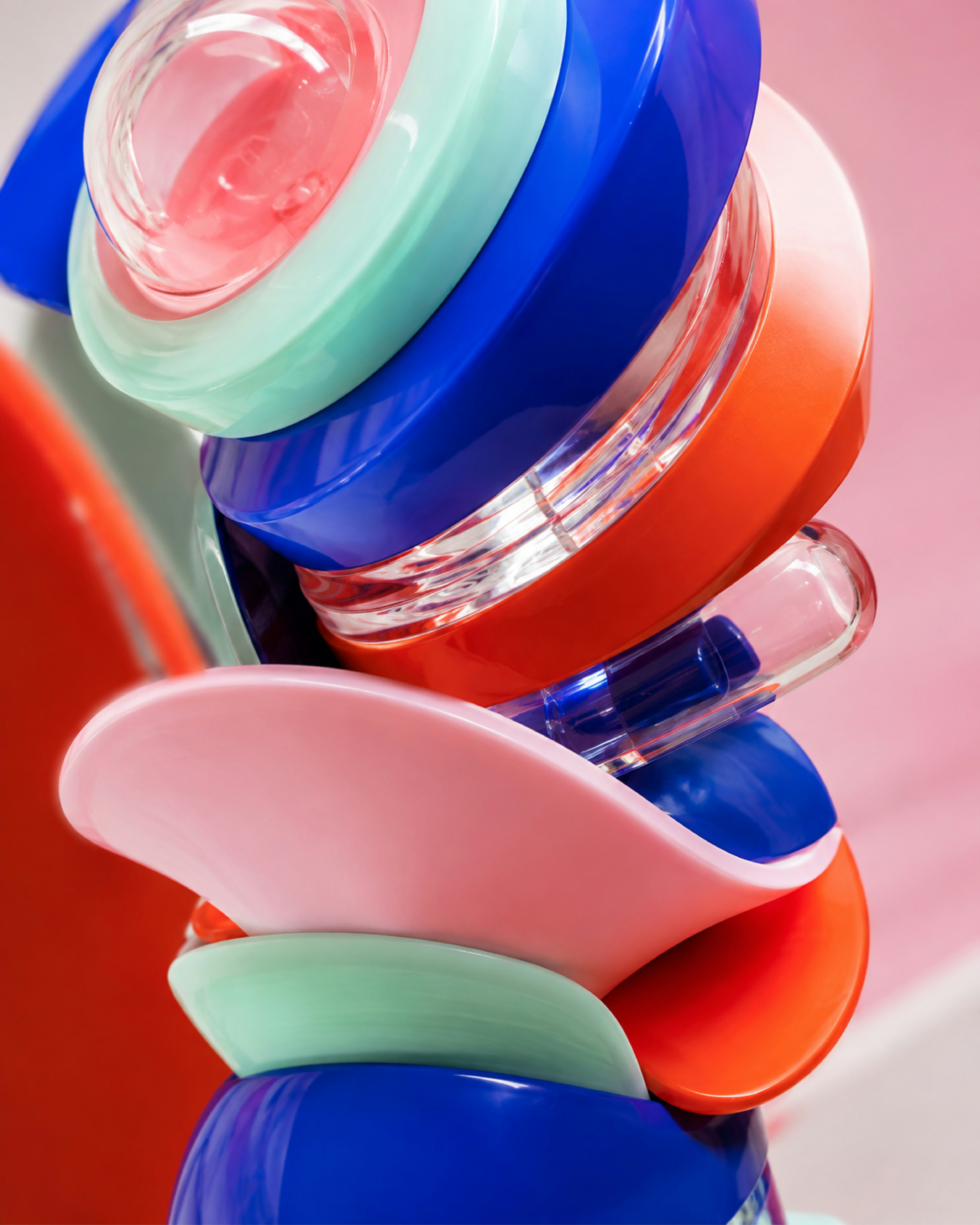 A stack of colorful plastic bowls and clear containers on a pink surface