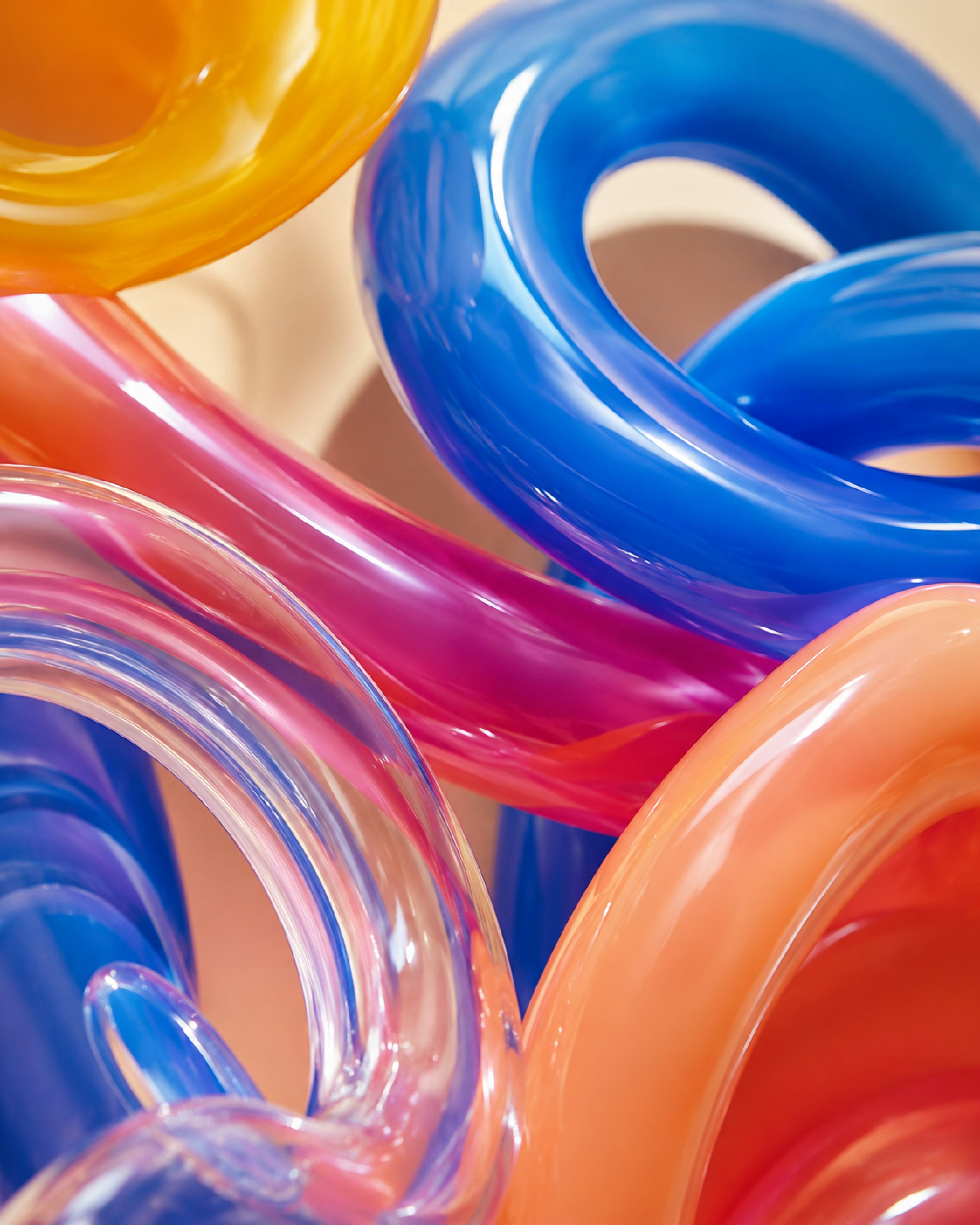 Intertwined translucent glass tubes in vibrant shades of blue, orange, and pink