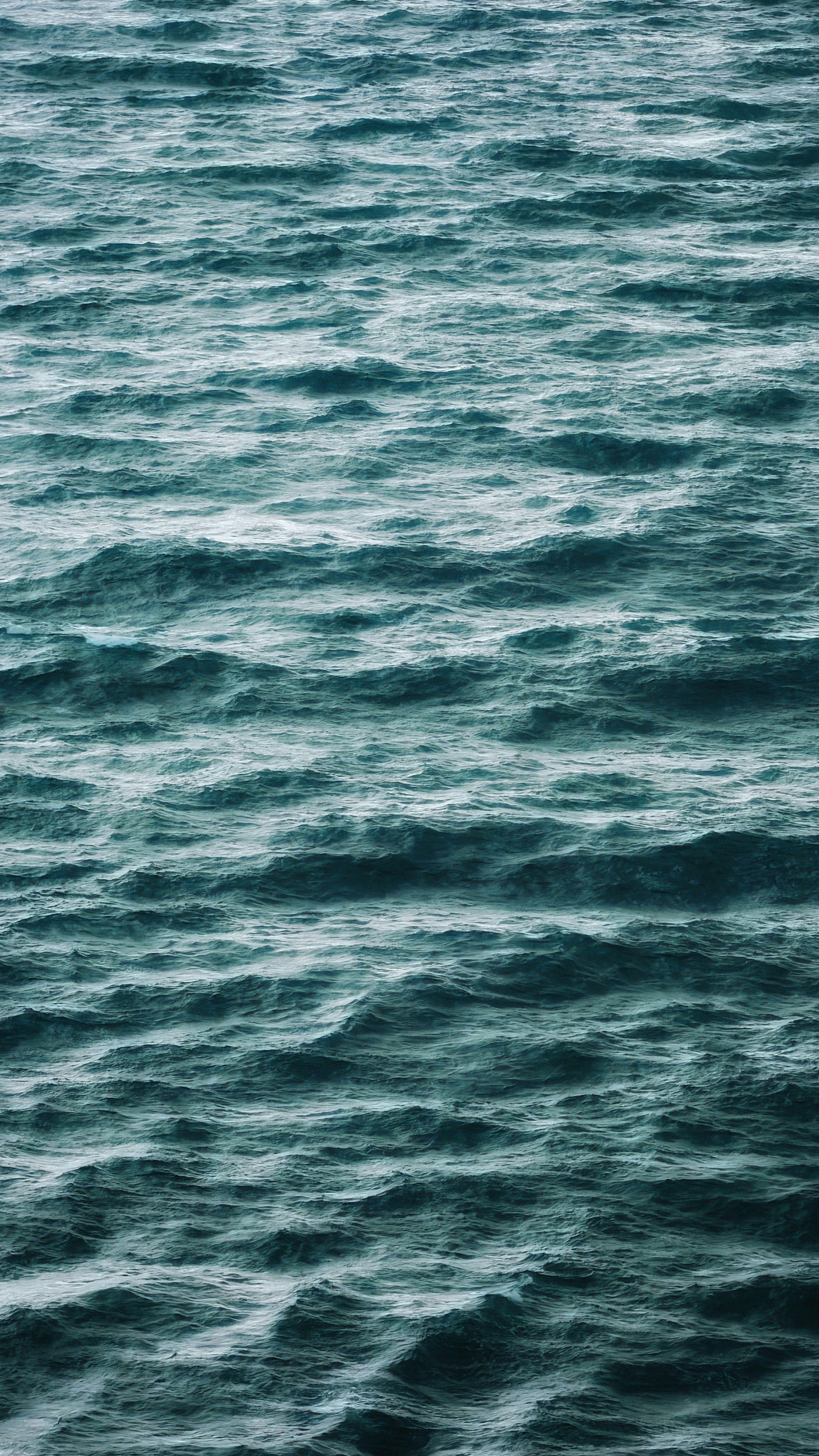 Vagues océaniques bleu sarcelle foncé avec des crêtes en mousse blanche en motif rythmé