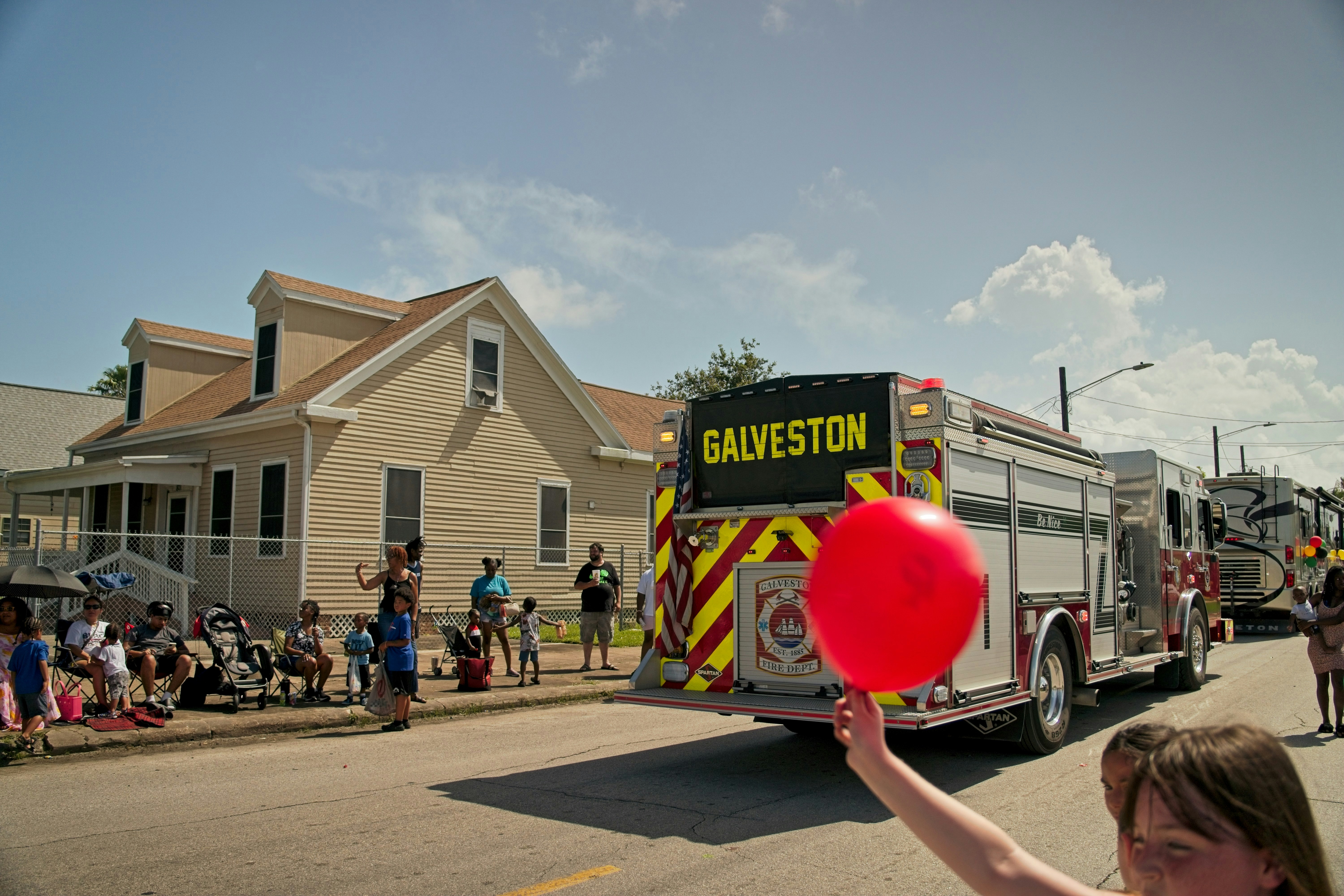 A Galveston fire truck driving down a street during a sunny parade
