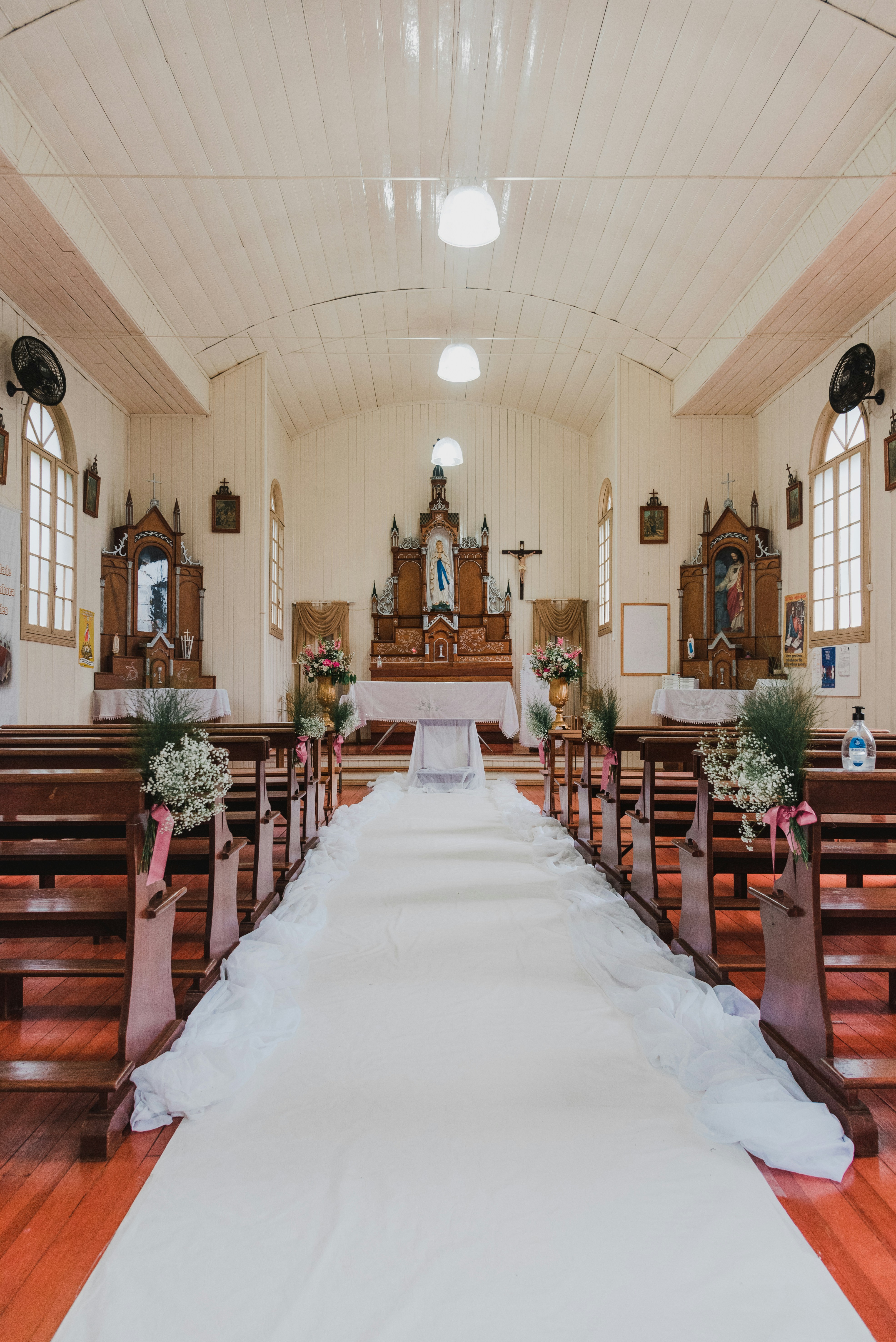 A white aisle runner leading to an altar in a wooden church interior