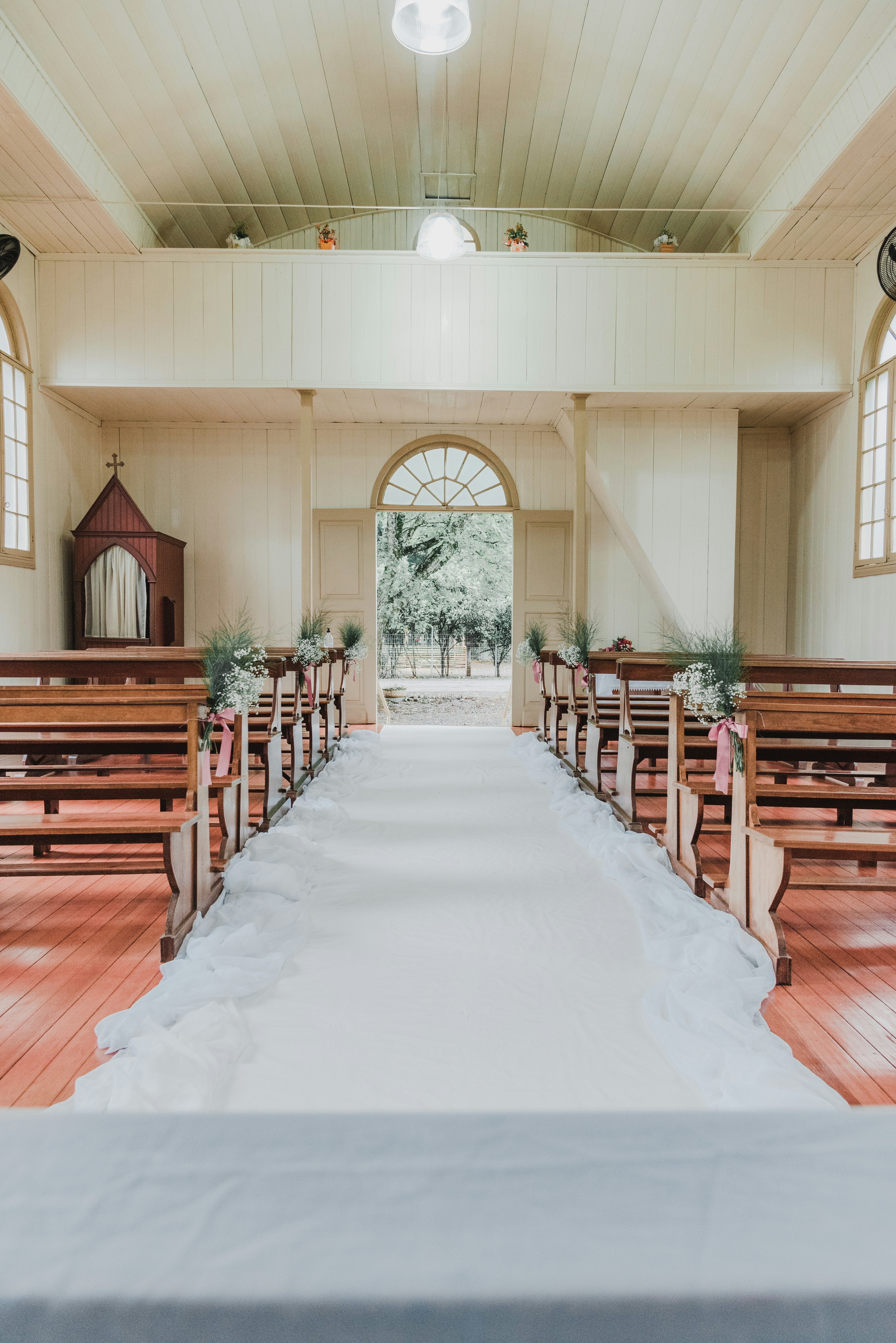 A white aisle runner between wooden pews in a bright church interior