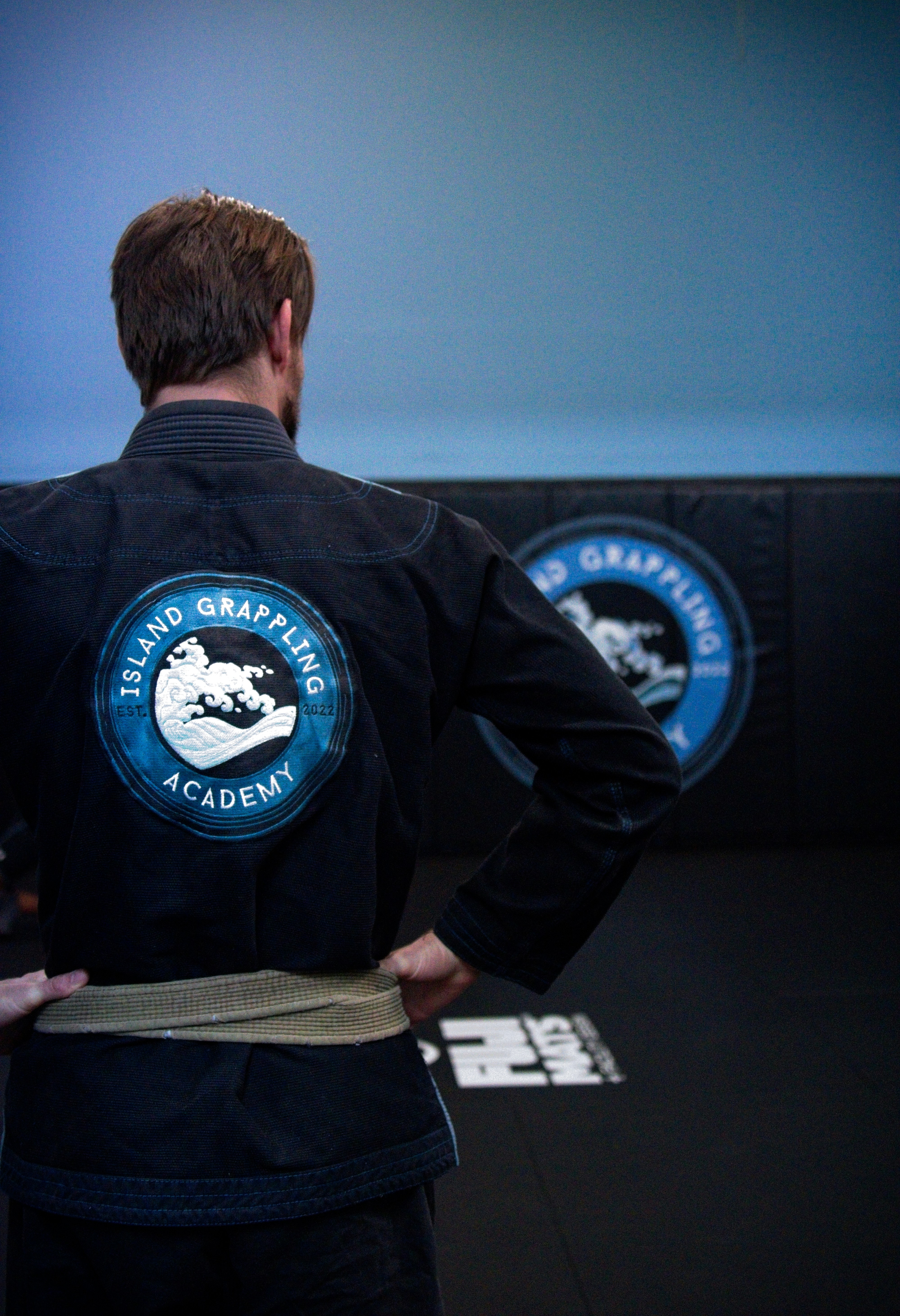 A person wearing a black gi with an Island Grappling Academy patch on the back