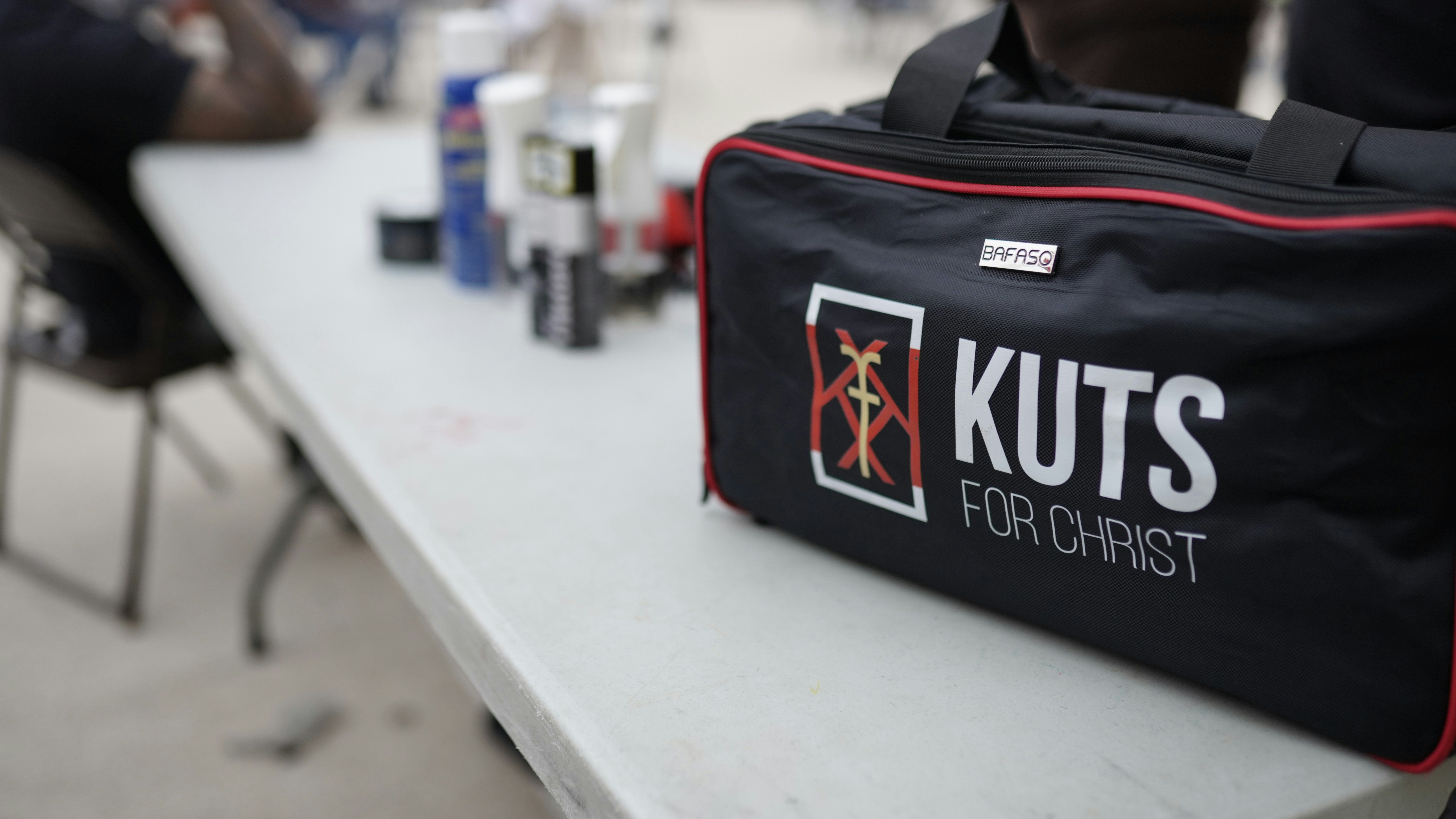 A black equipment bag with red trim on a white folding table