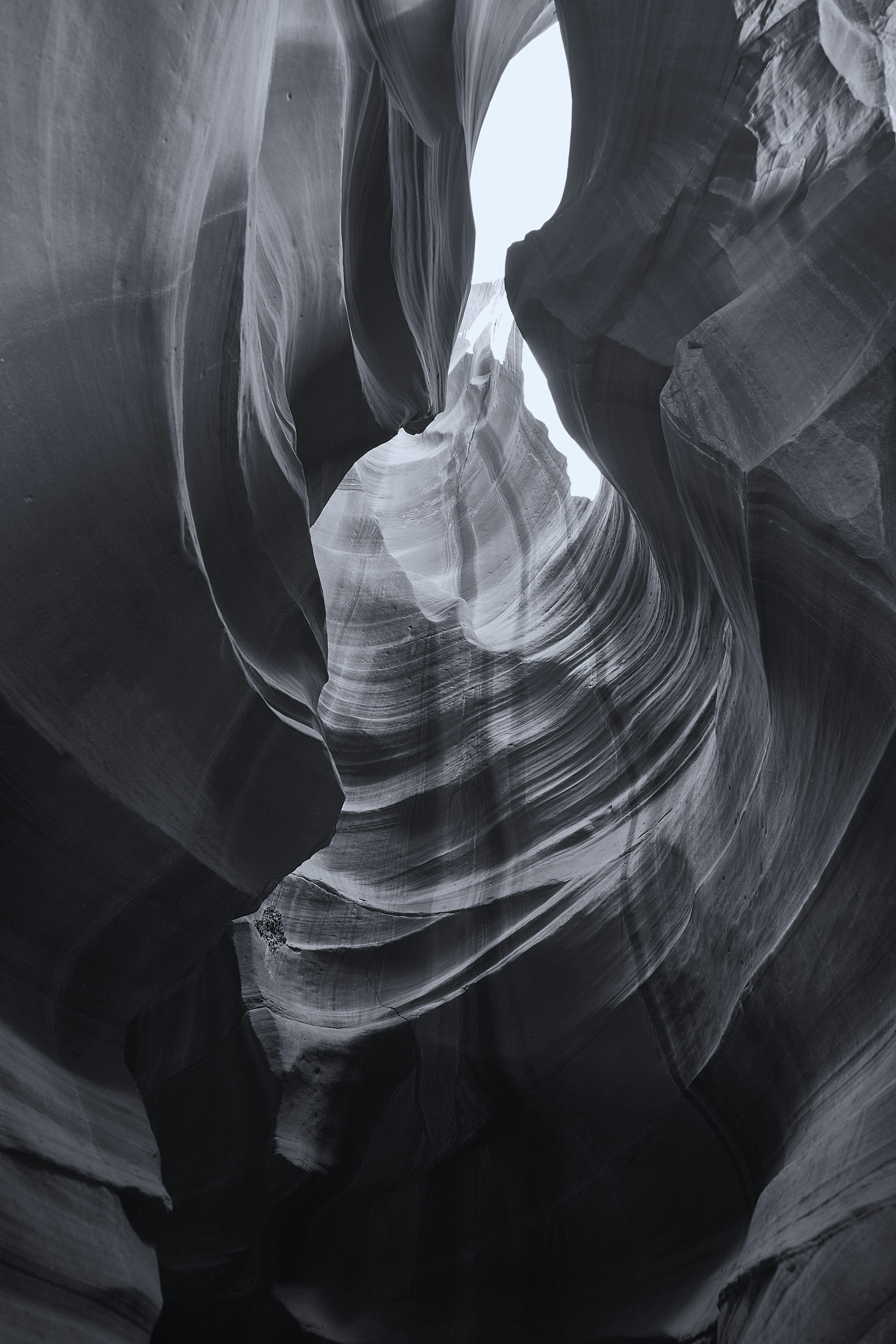 Smooth flowing sandstone walls of a narrow slot canyon in black and white