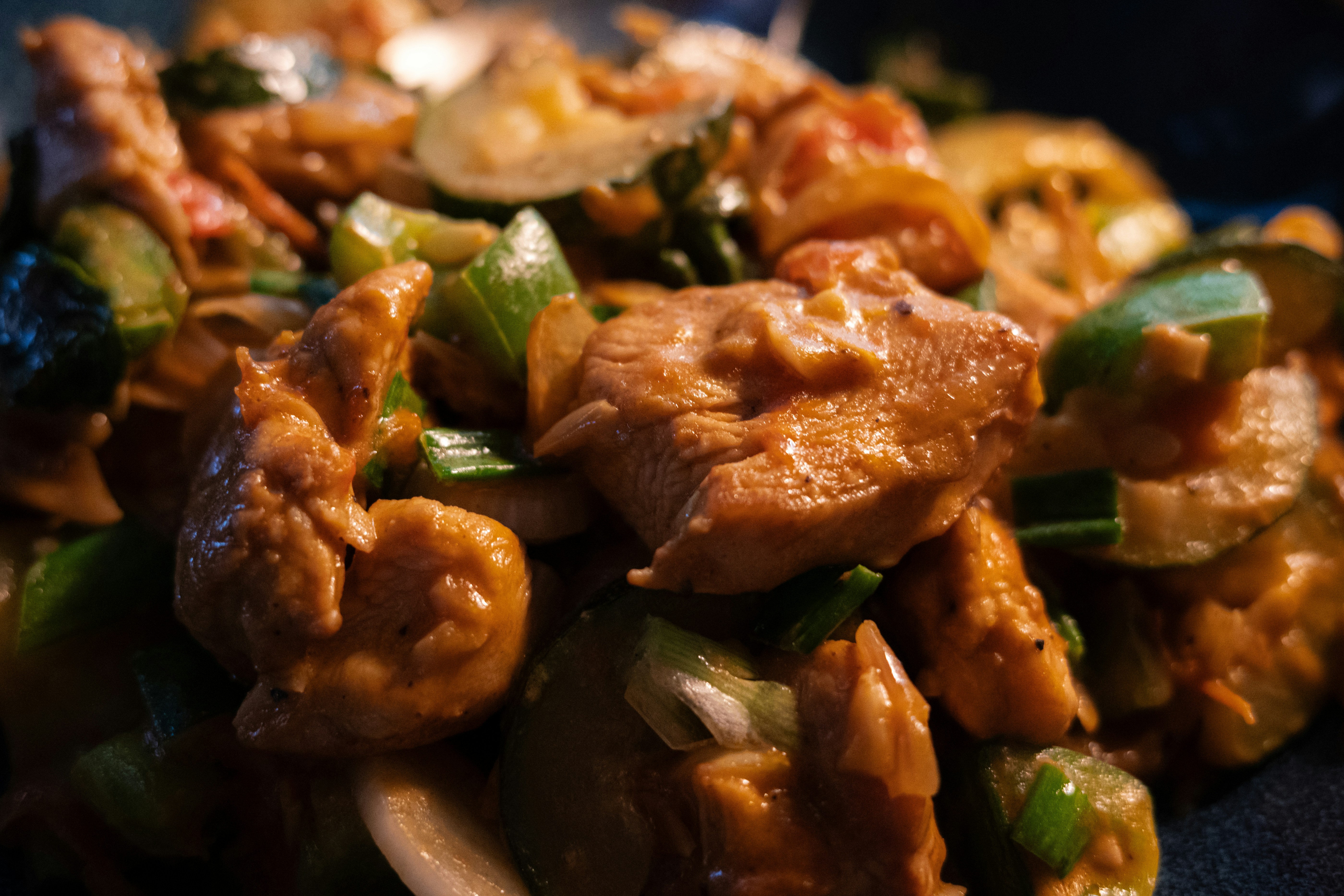 Stir-fried chicken pieces with sliced zucchini and green onions in a savory sauce