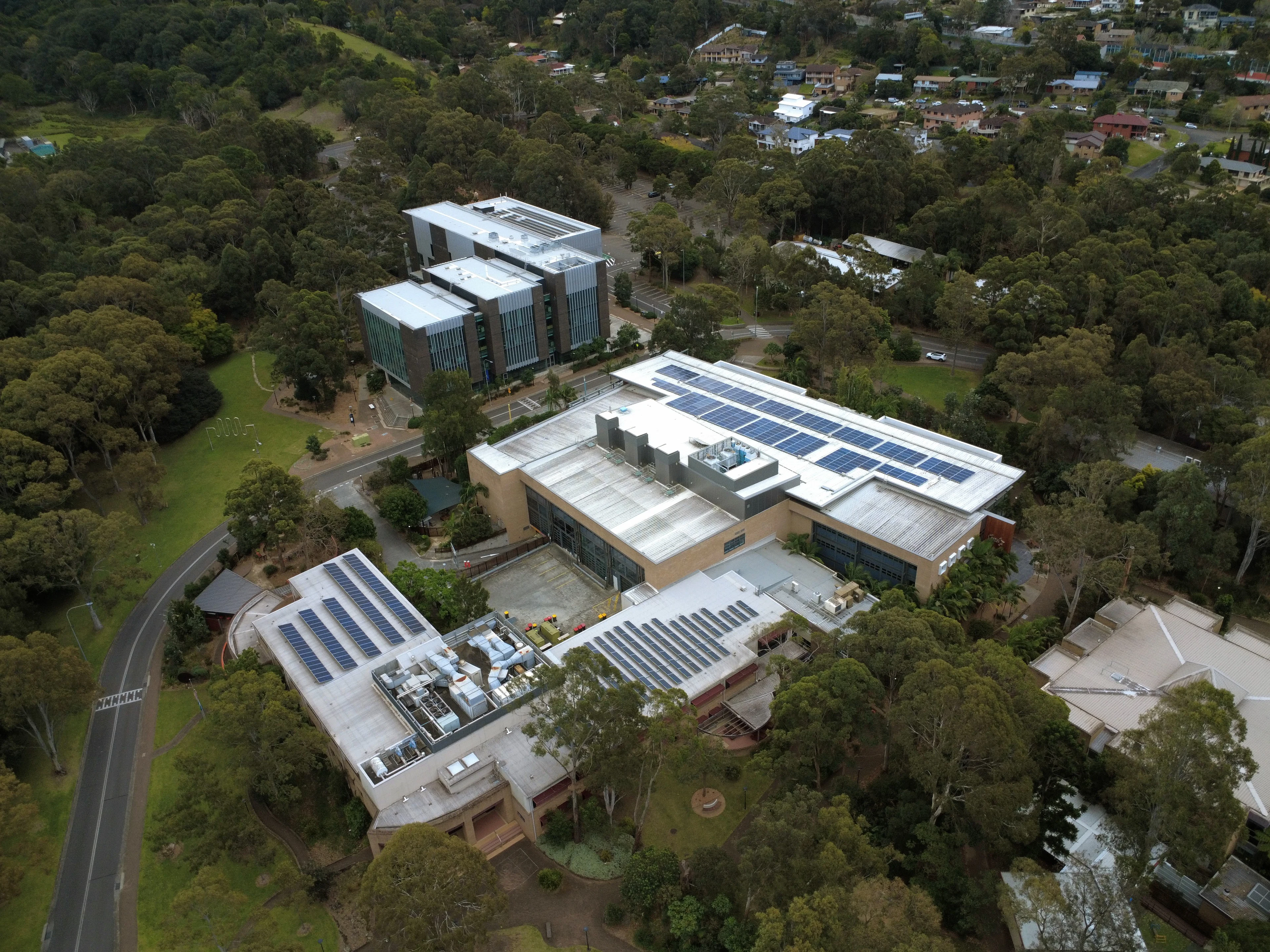 Imagen de referencia: edificios modernos con paneles solares entre árboles