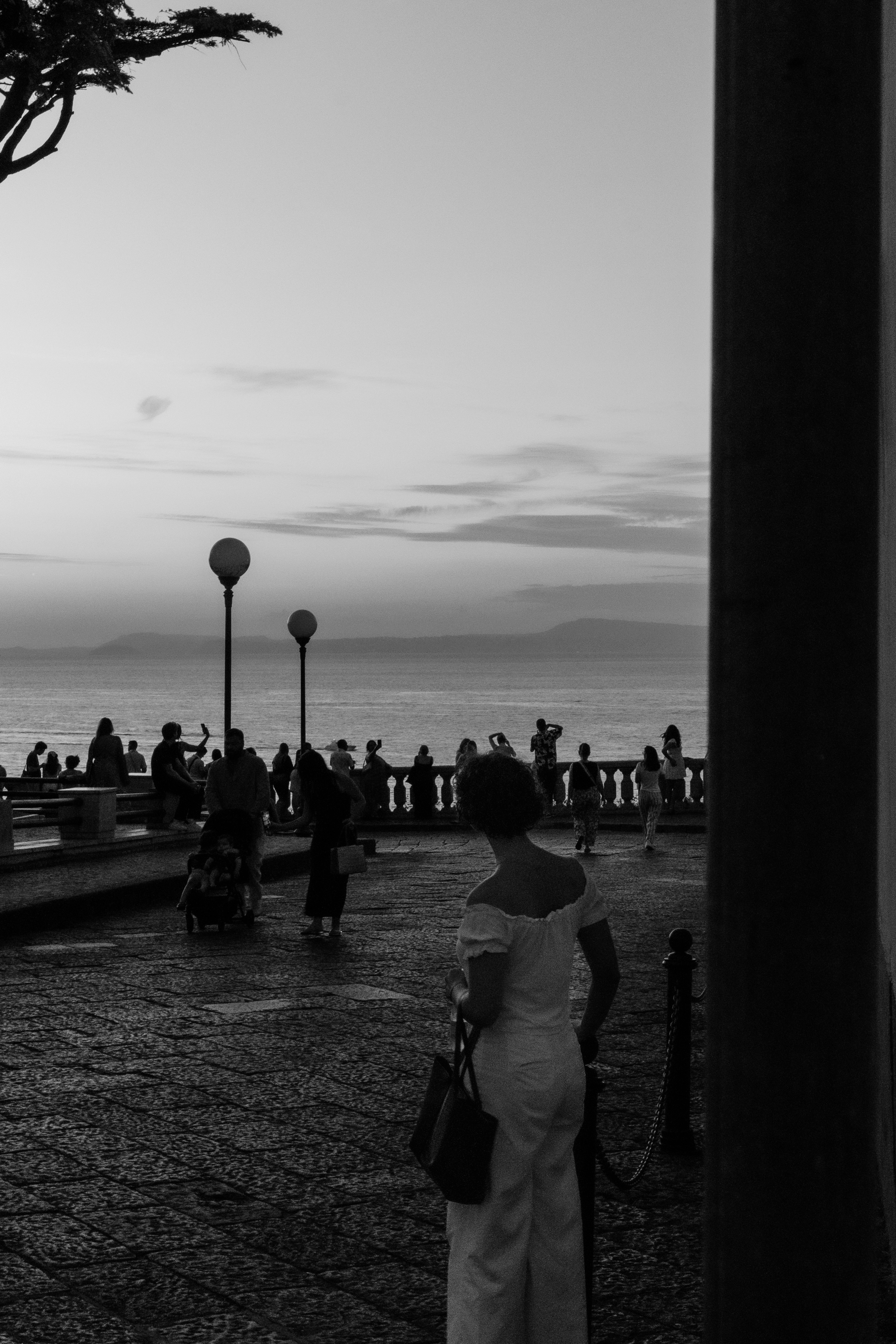 People on a stone promenade overlooking the sea at golden hour