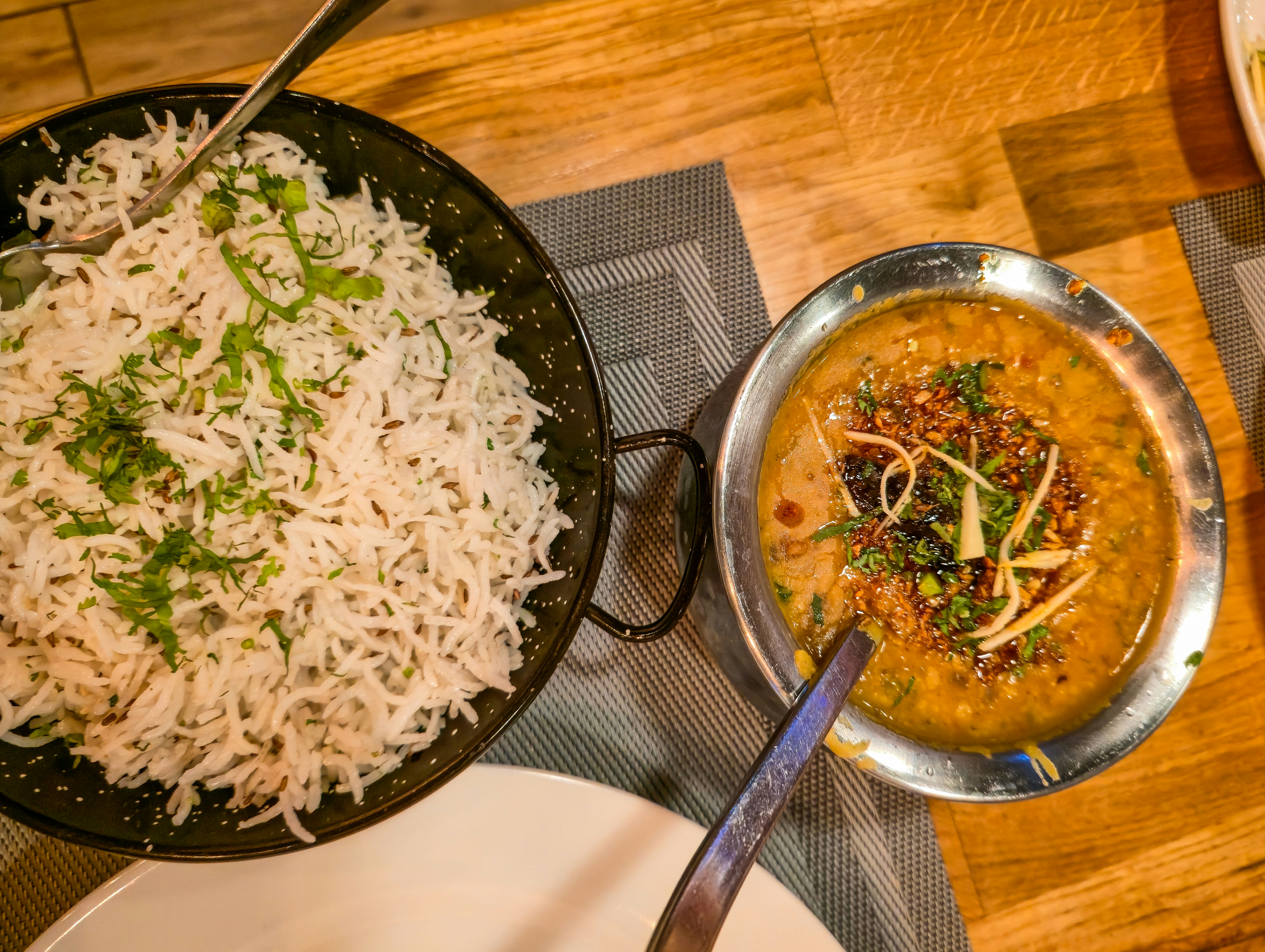 A bowl of basmati rice and a bowl of dal on a wooden table