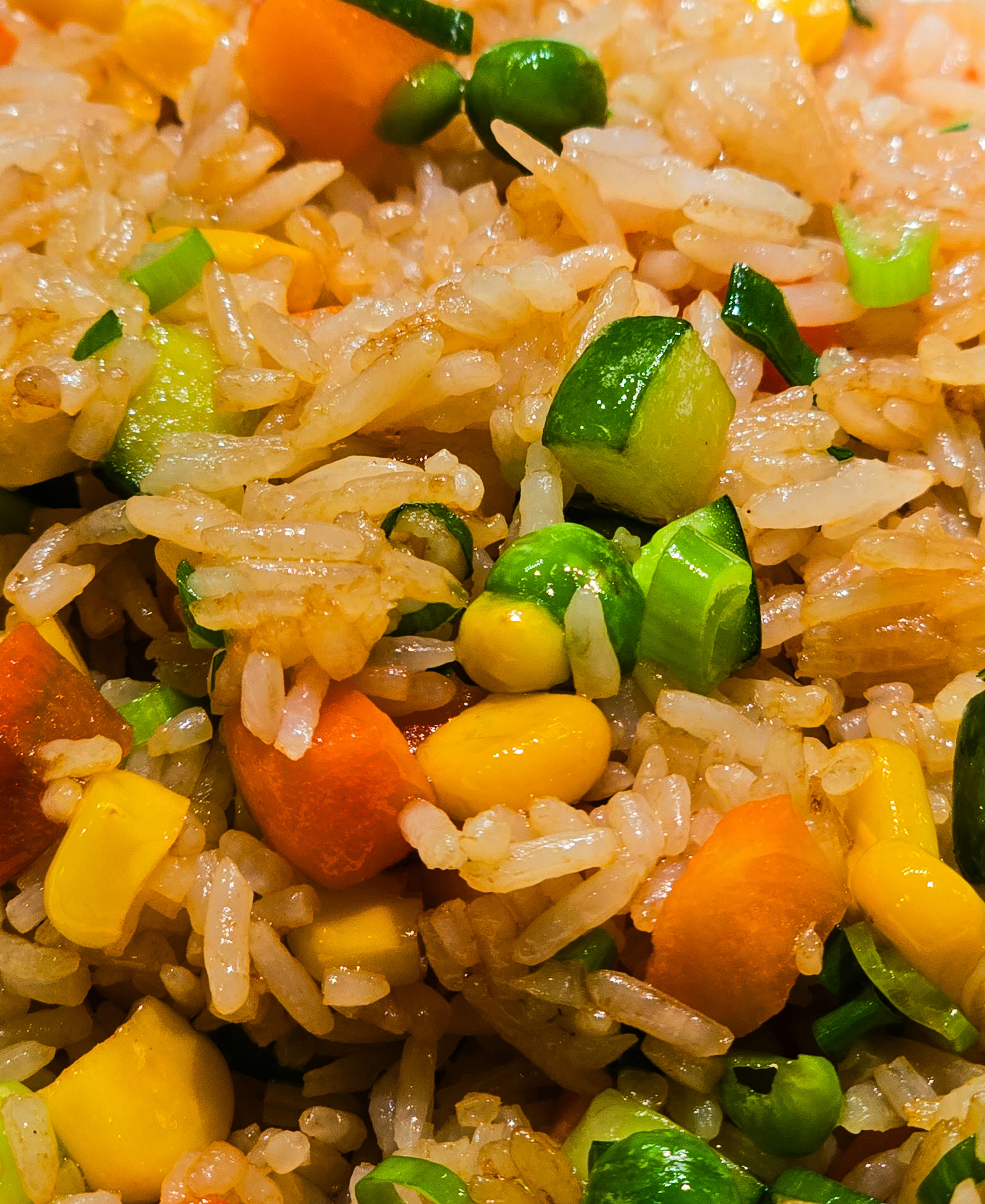 A close-up of fried rice mixed with carrots, corn, peas, and green onions