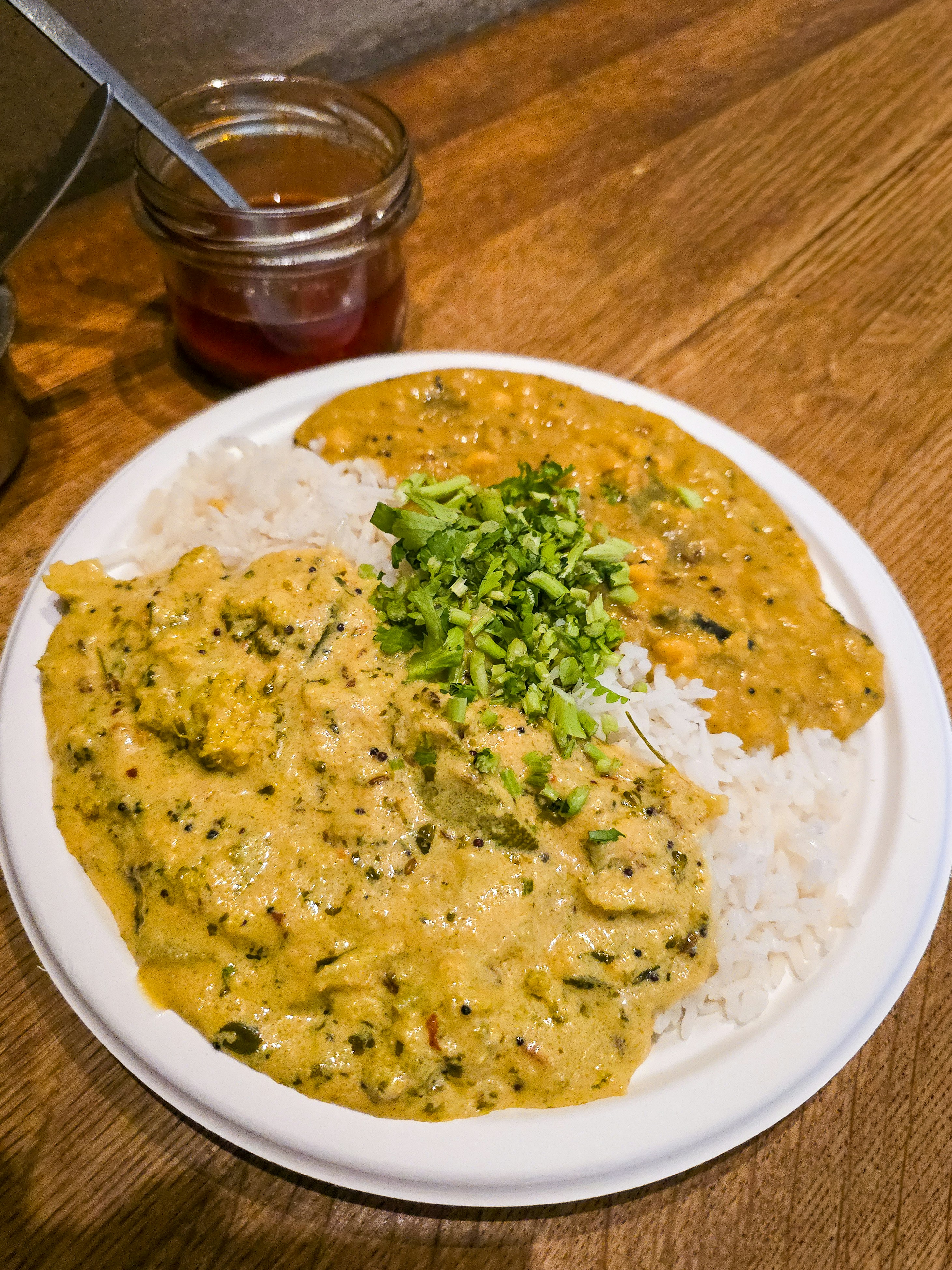 A plate of rice with two curries, topped with fresh coriander