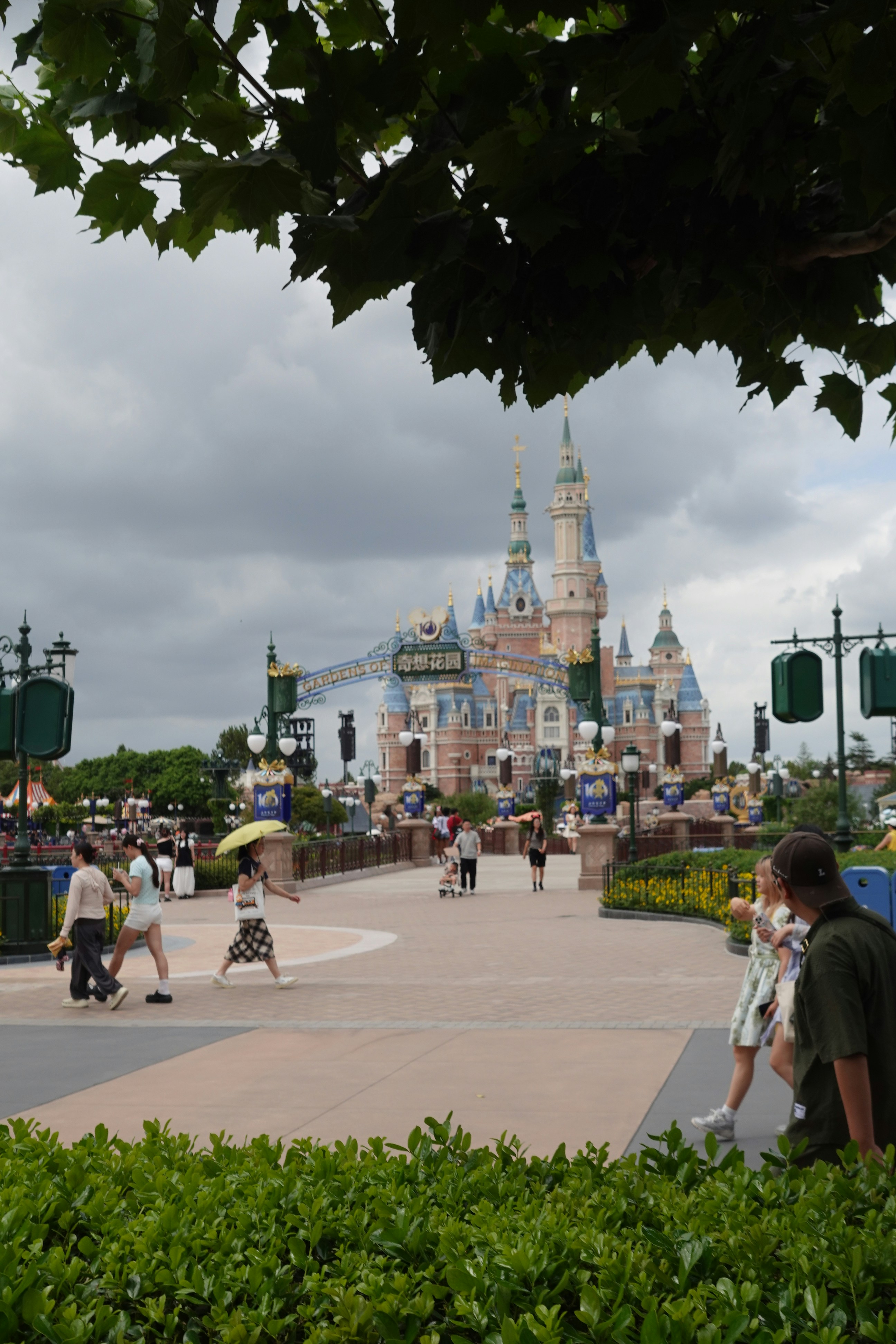 上海ディズニーランドの大きな城へ向かう舗装された道を歩く人々
