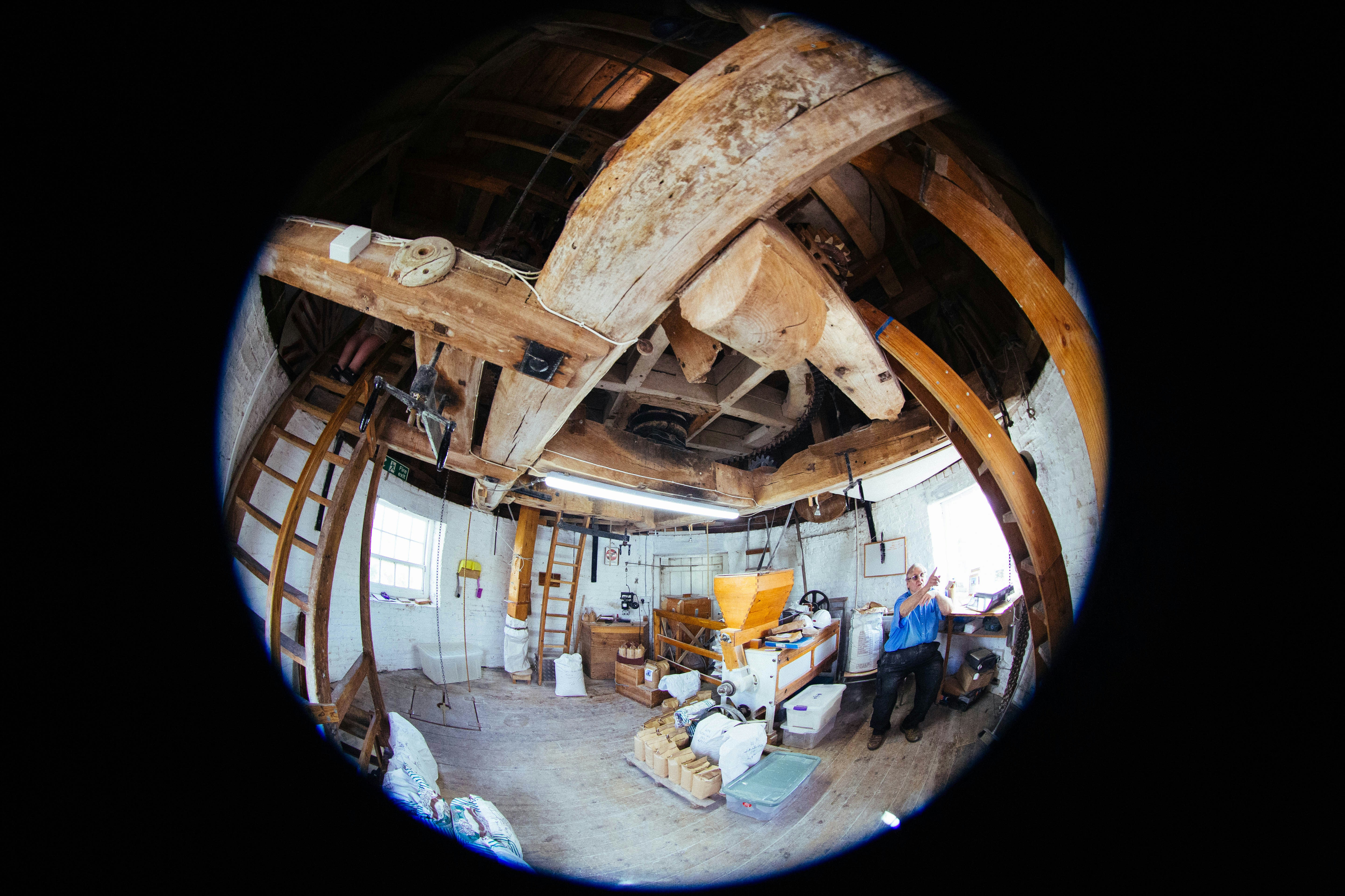 A person in a blue shirt inside a rustic wooden windmill interior