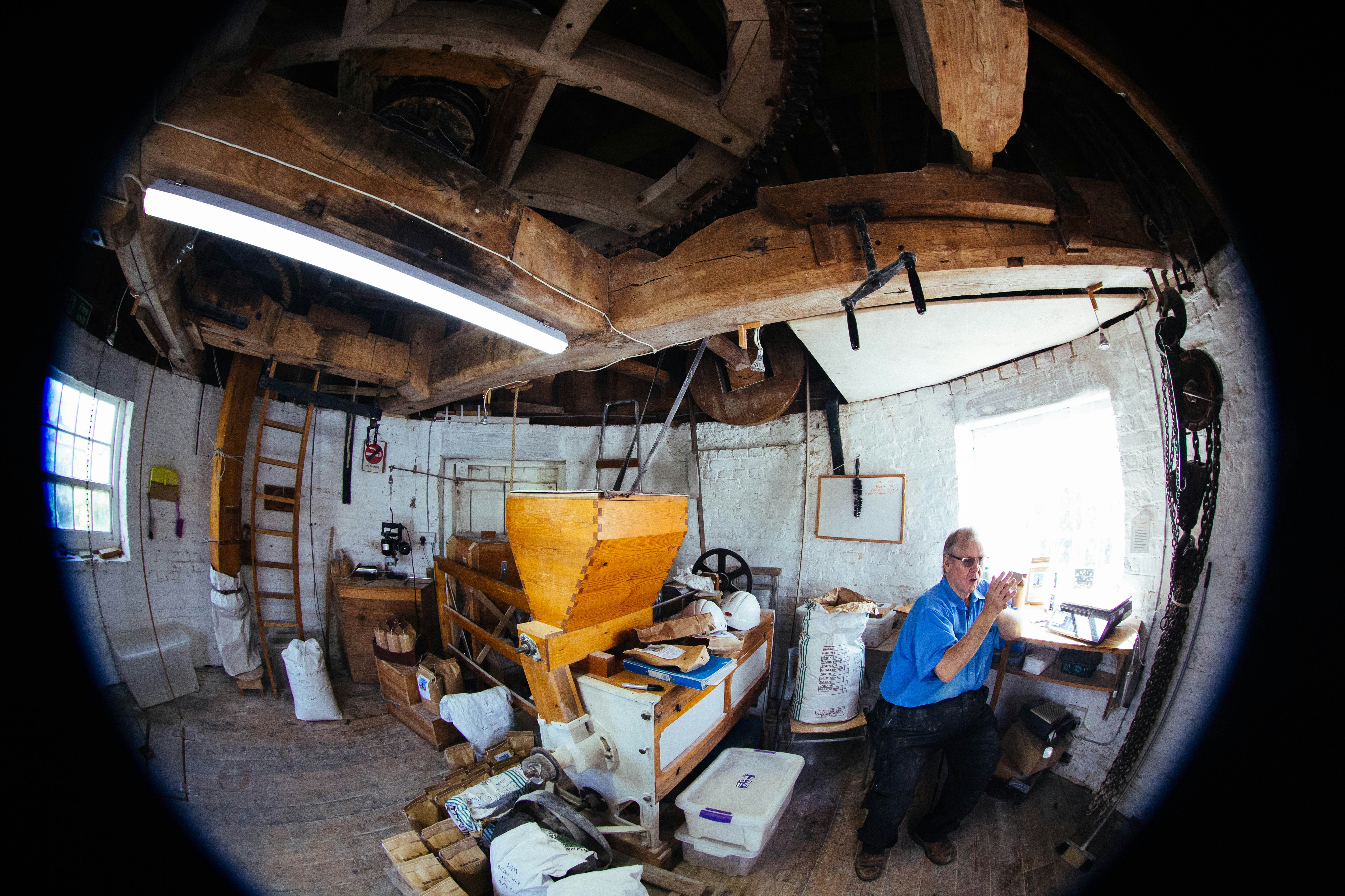 A man in a blue shirt sitting inside a rustic wooden windmill