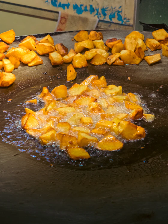 Potatoes frying golden on a wide griddle