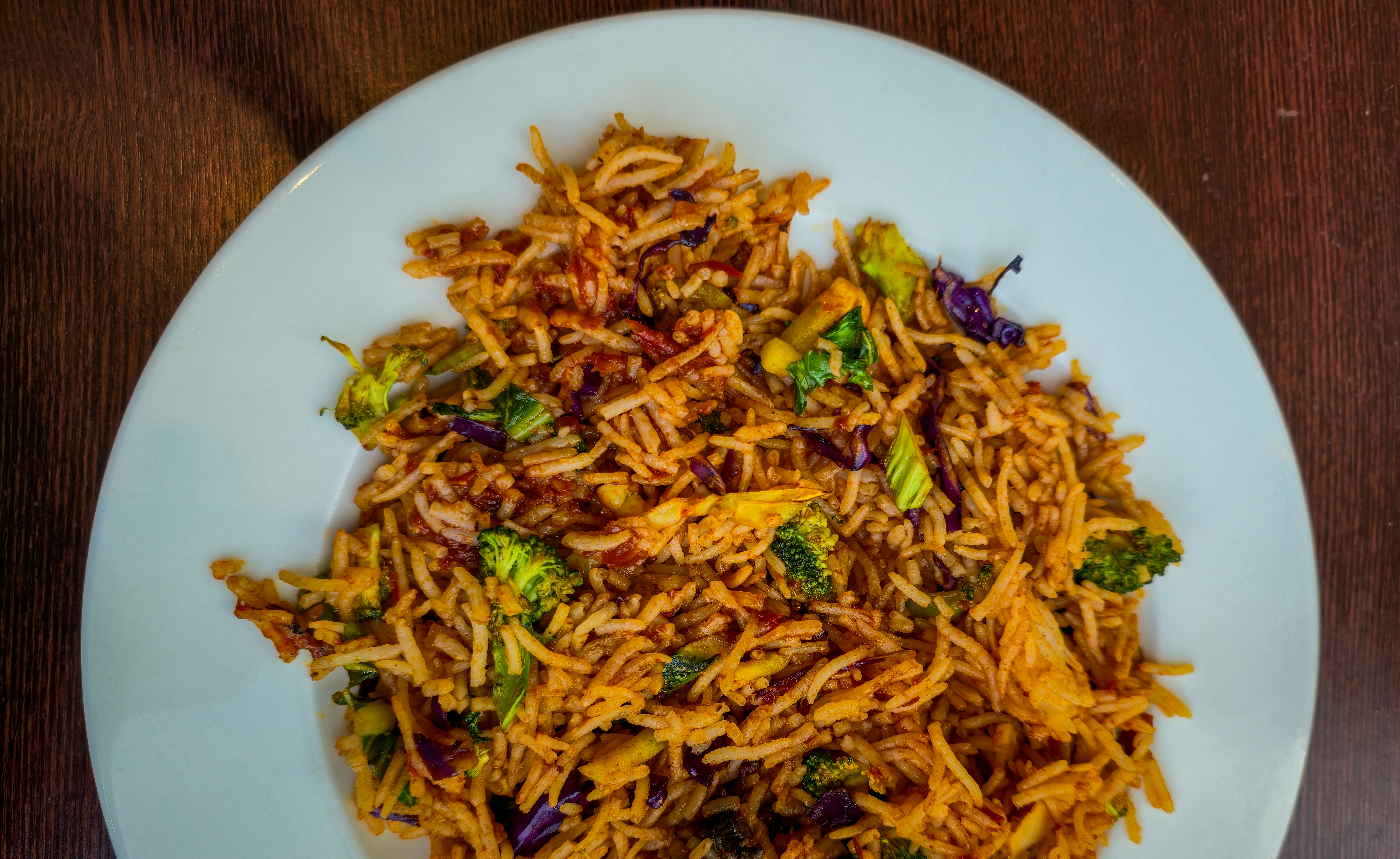 A plate of vegetable fried rice with broccoli and purple cabbage