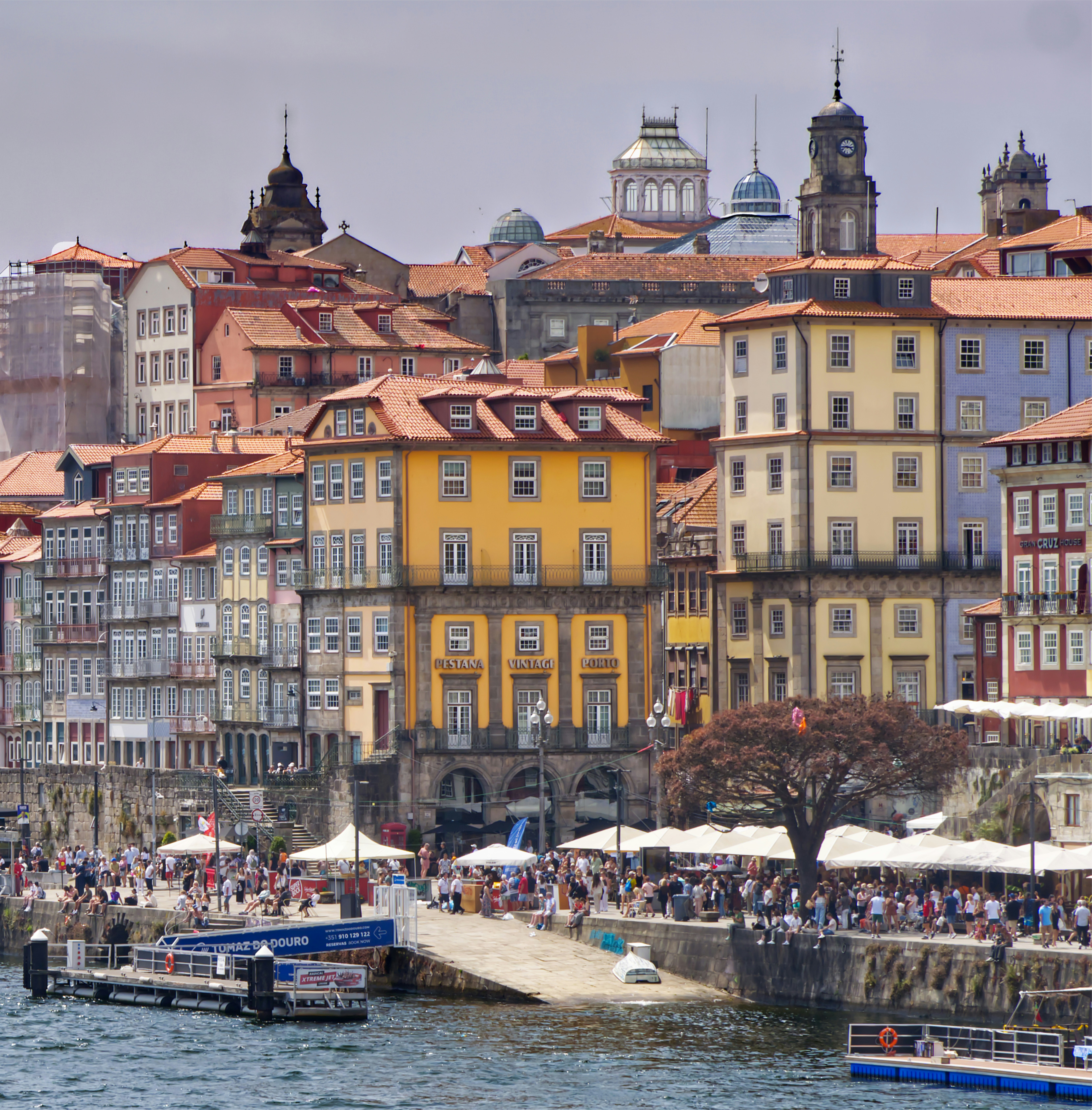 Colorful buildings along the Douro River waterfront in Porto, Portugal, with a busy promenade