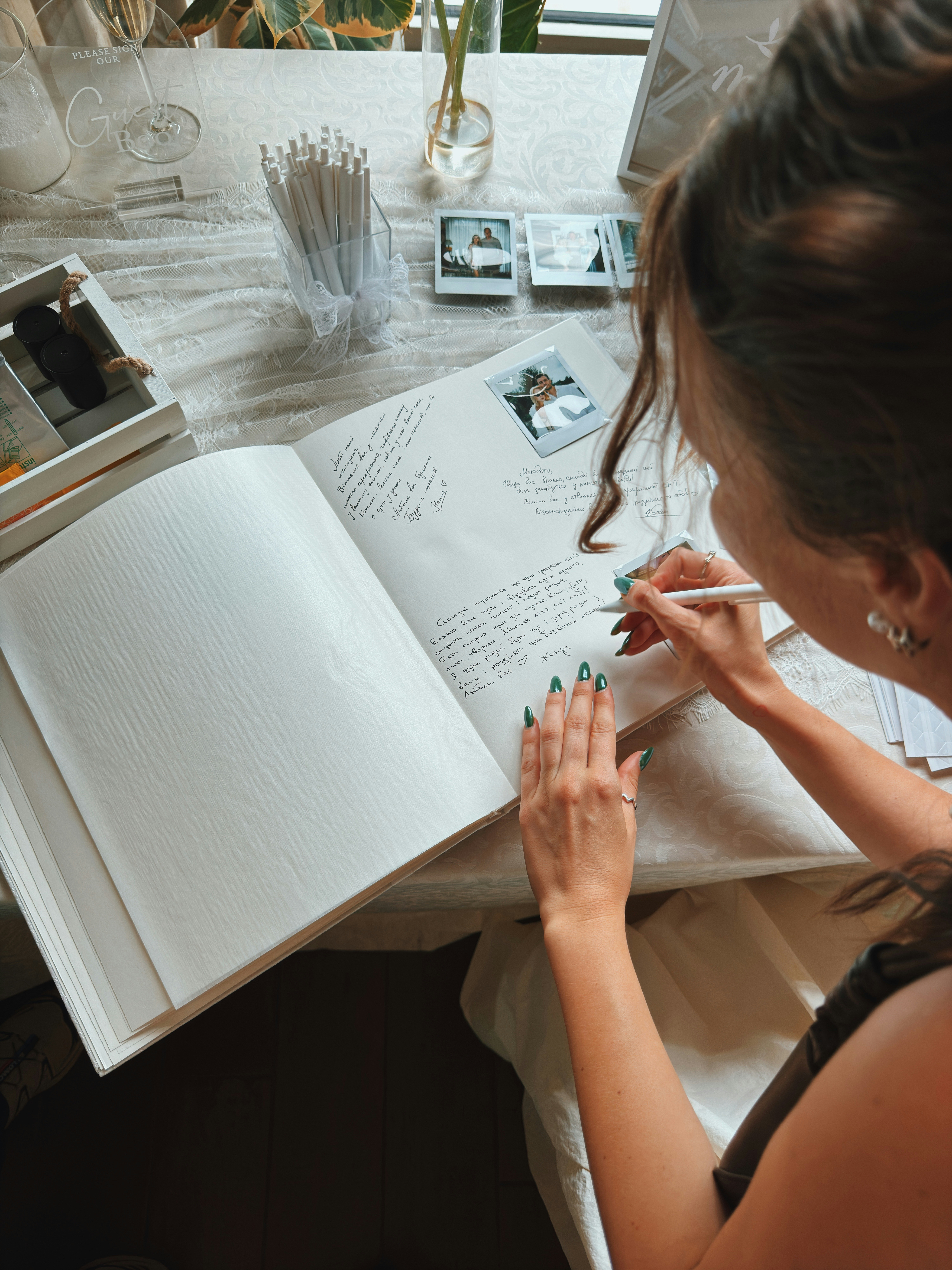 A woman writing in a wedding guest book with a white pen