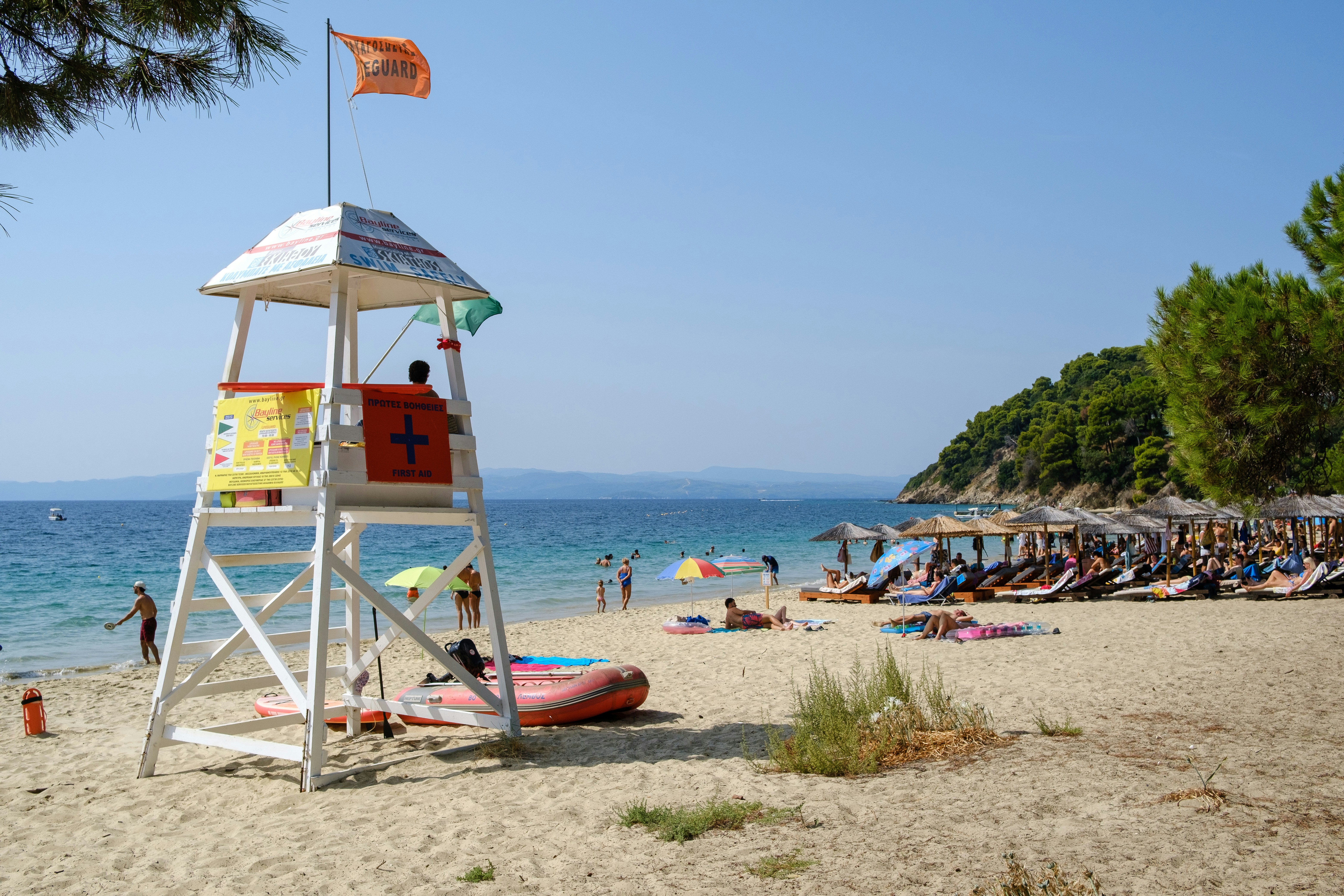 Ein weißer Rettungssturm an einem Sandstrand, an dem Menschen am Wasser entspannen