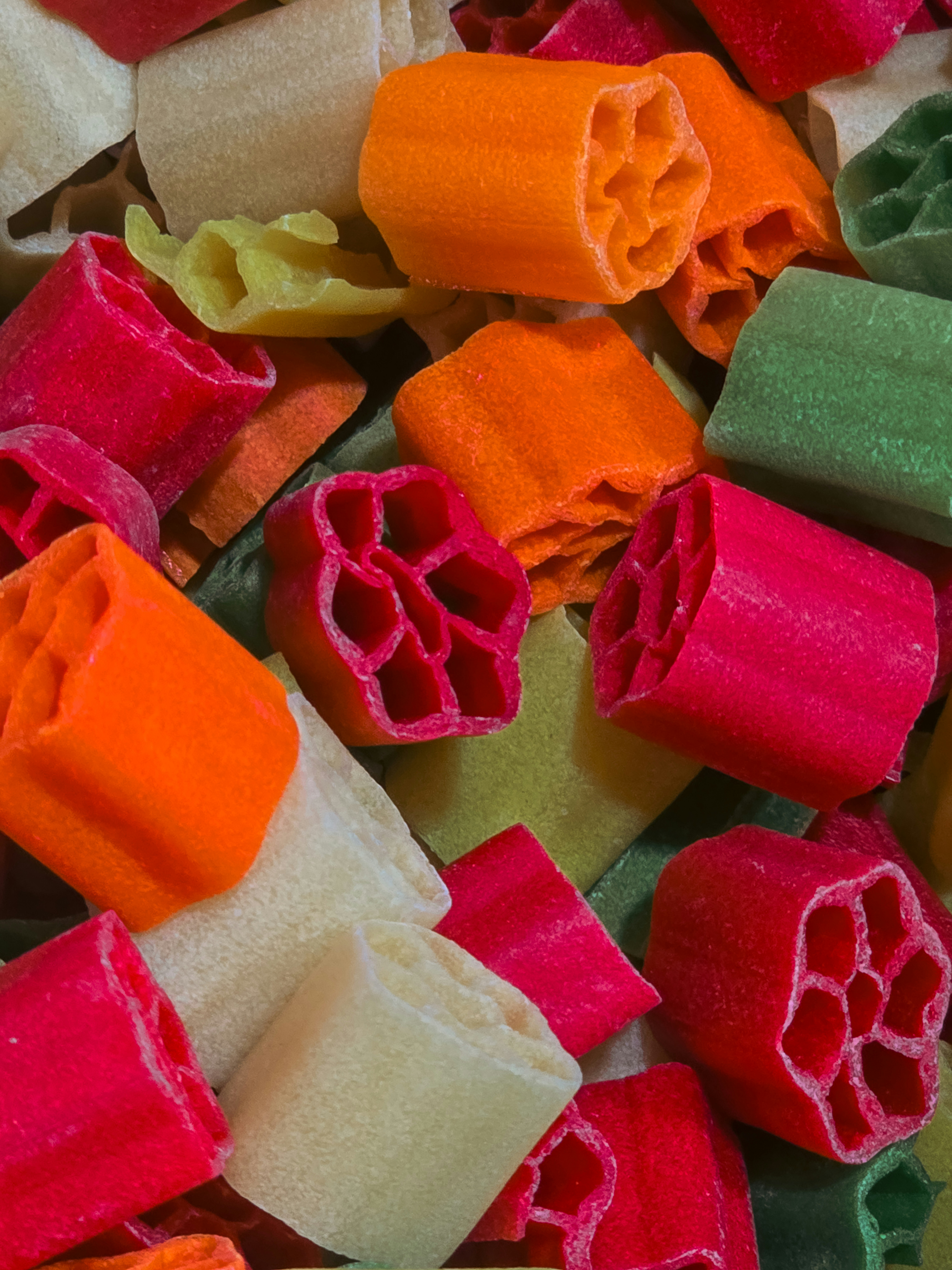 A pile of colorful red, orange, green, and white wagon wheel pasta snacks