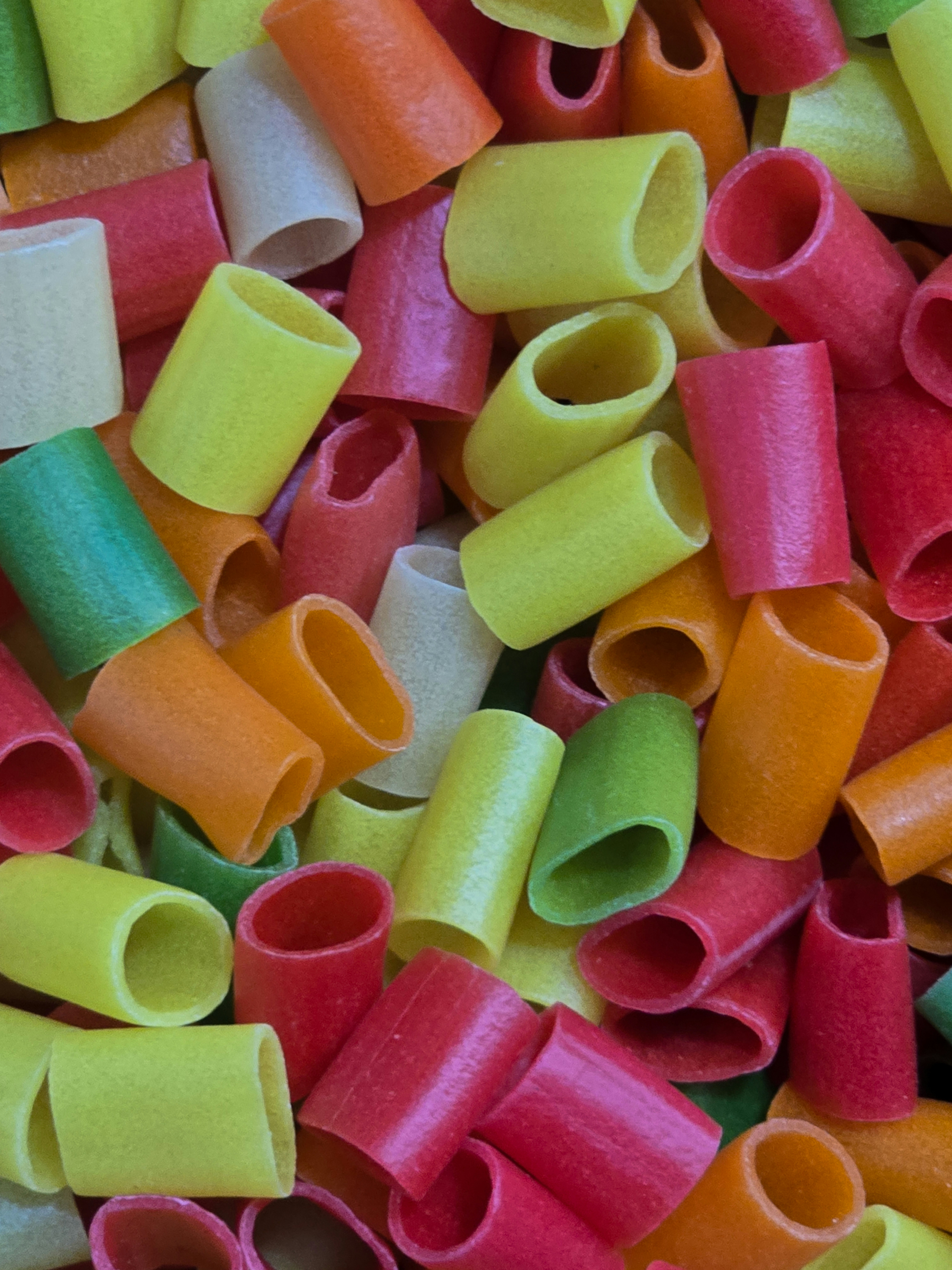 A pile of colorful tube-shaped fryums in red, yellow, orange, and green