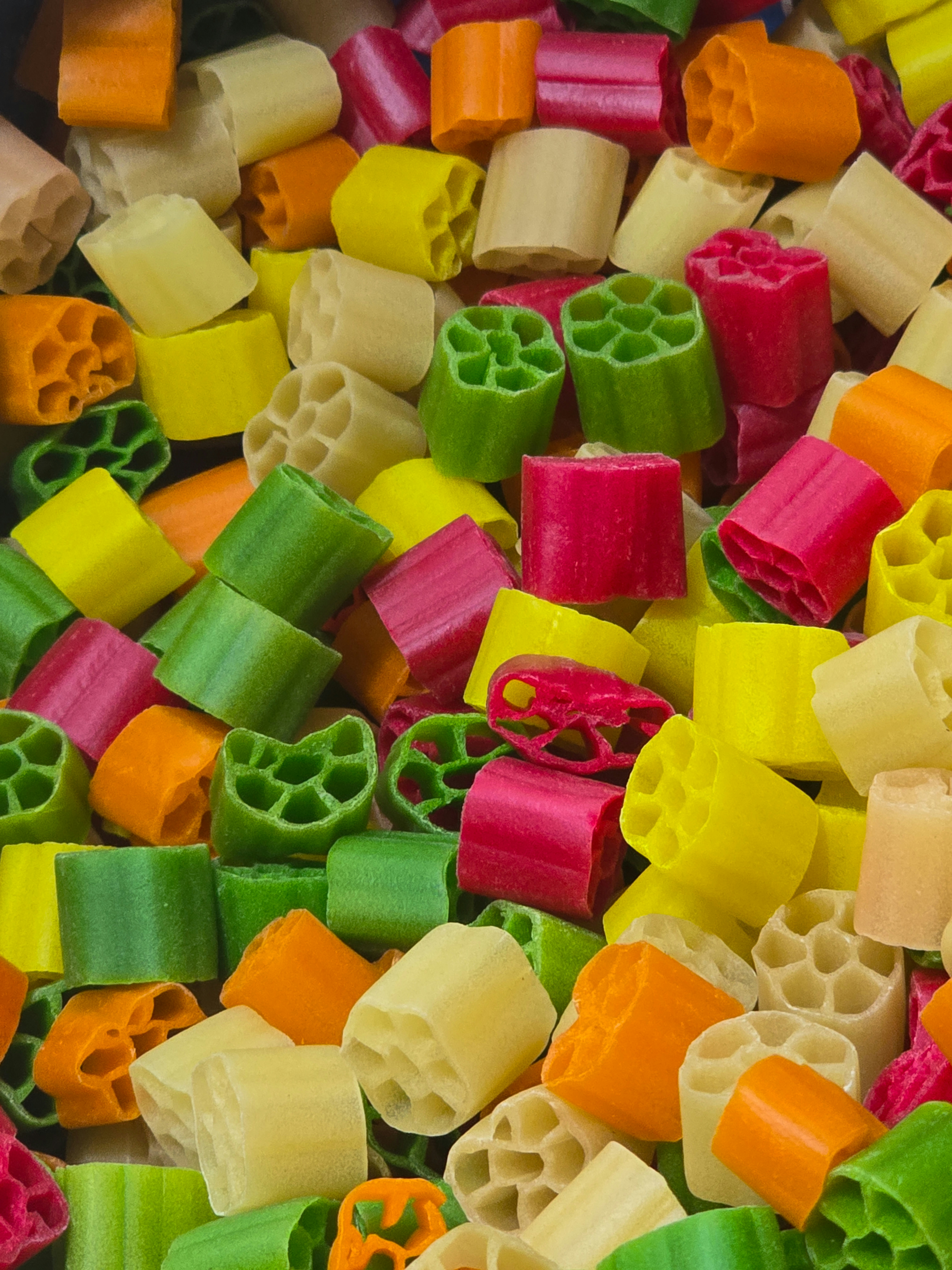 A pile of colorful wagon wheel pasta in red, green, yellow, and orange