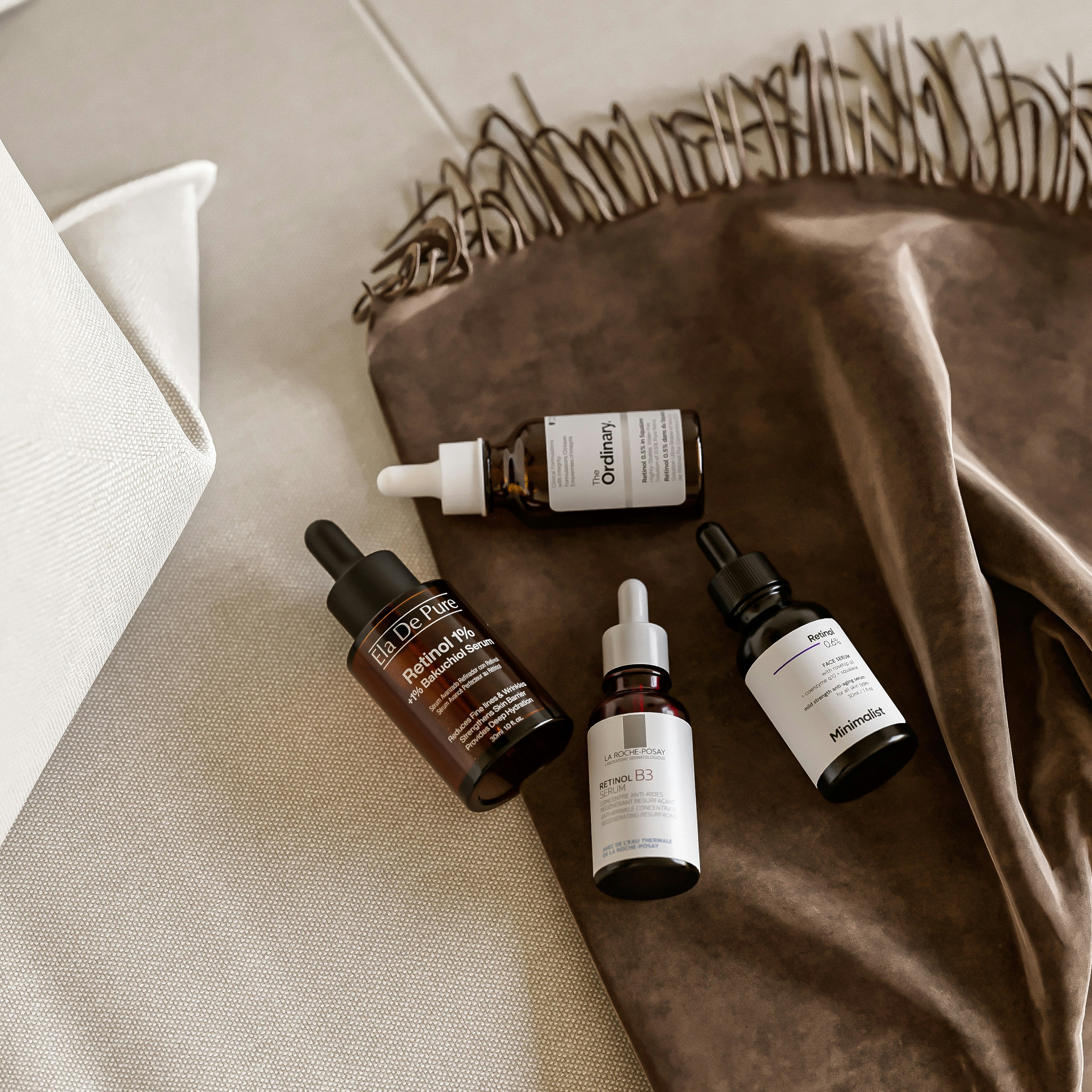 Four glass dropper bottles of facial serum on a brown velvet cloth