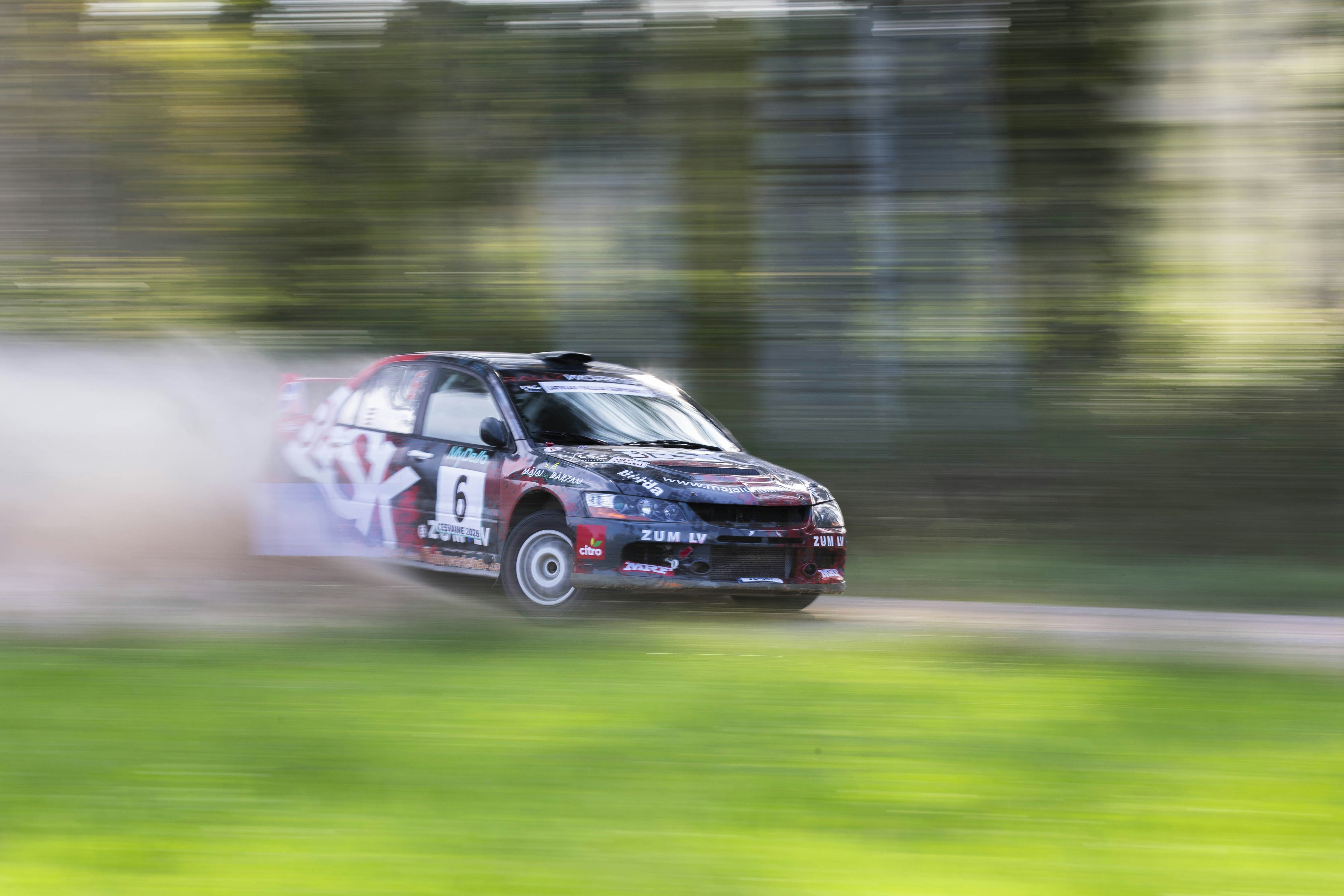 A rally car drifting on a dirt track with motion blur