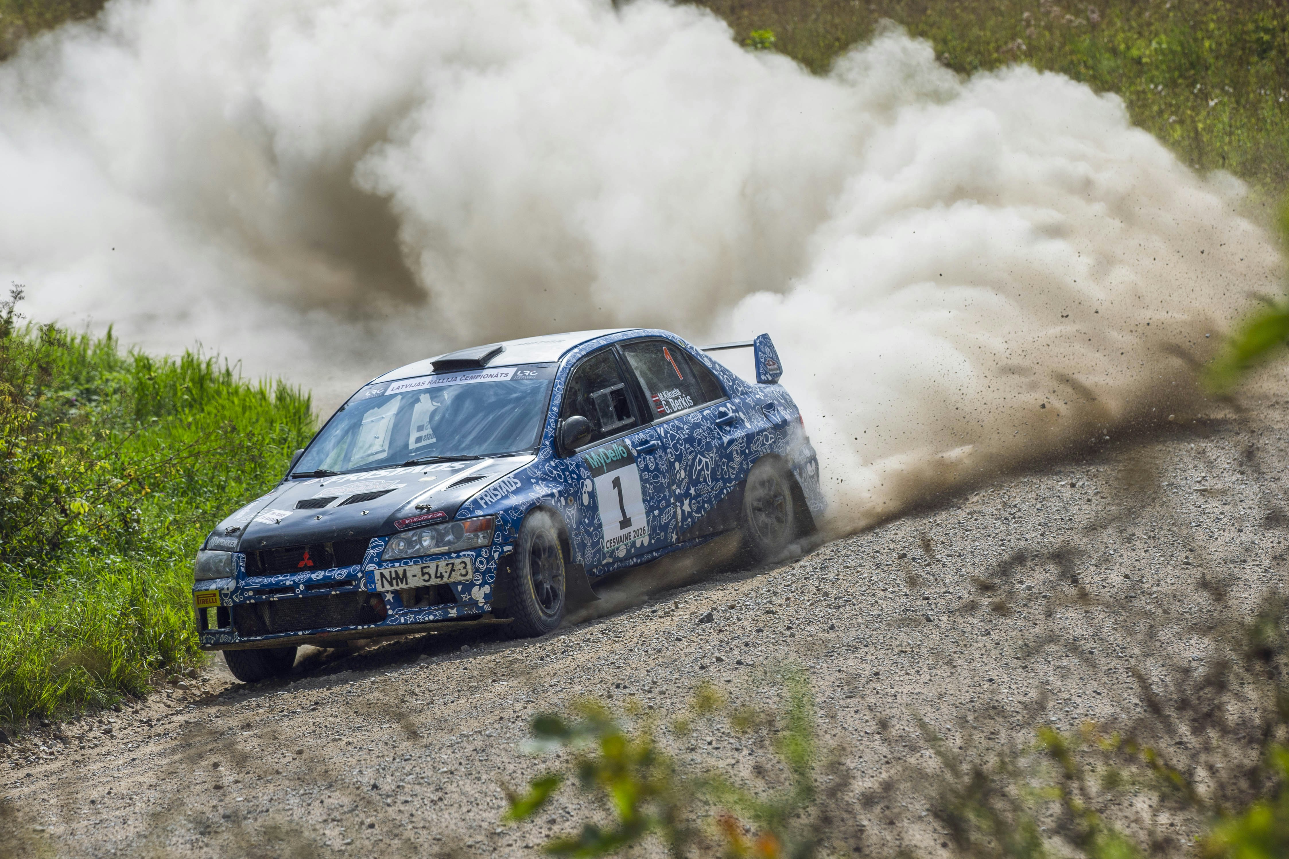 A blue rally car drifting on a dirt road with a large dust cloud