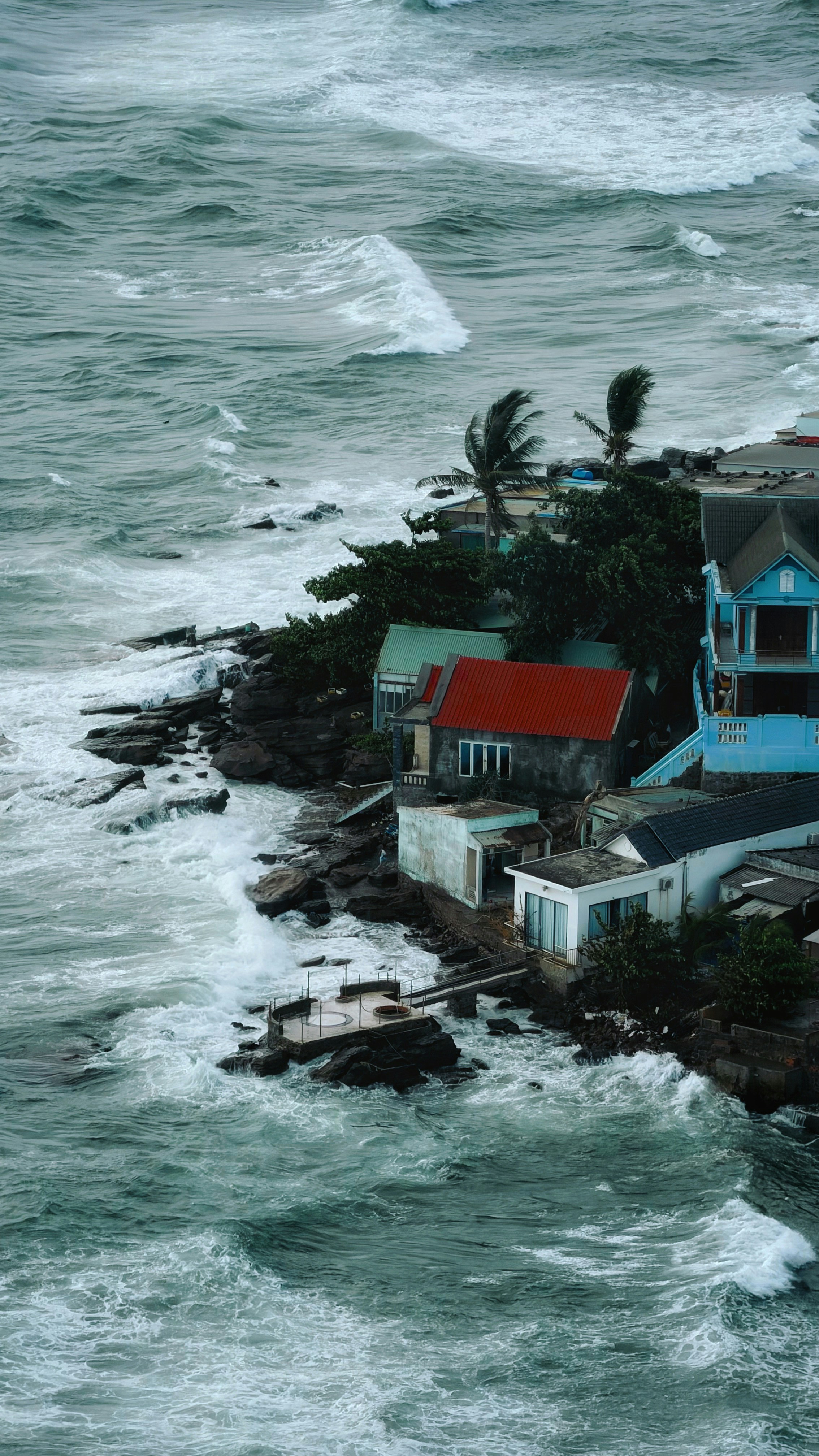Des maisons aux toits colorés sur un littoral rocheux au bord des vagues déferlantes
