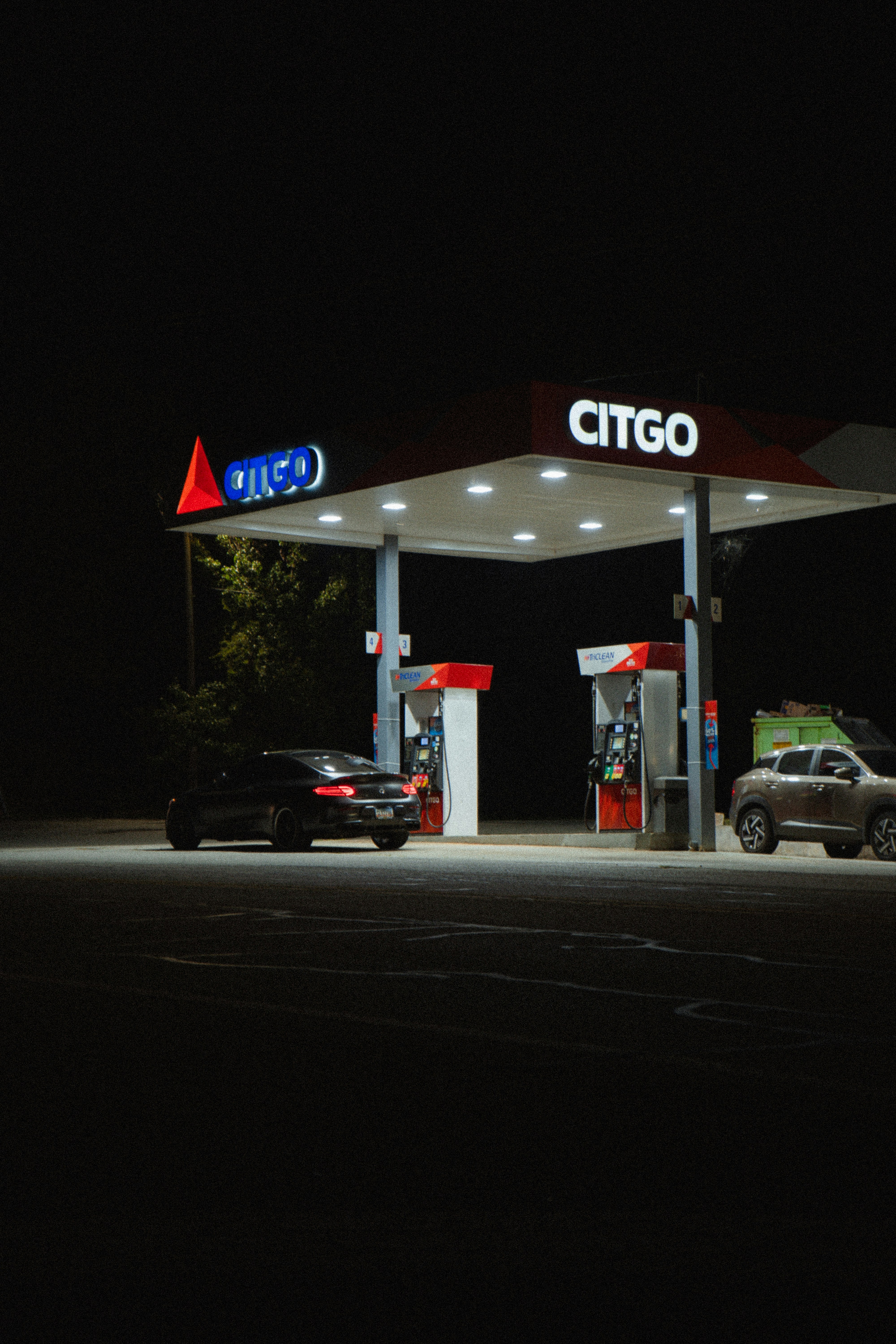 A dark car parked at a brightly lit Citgo gas station at night
