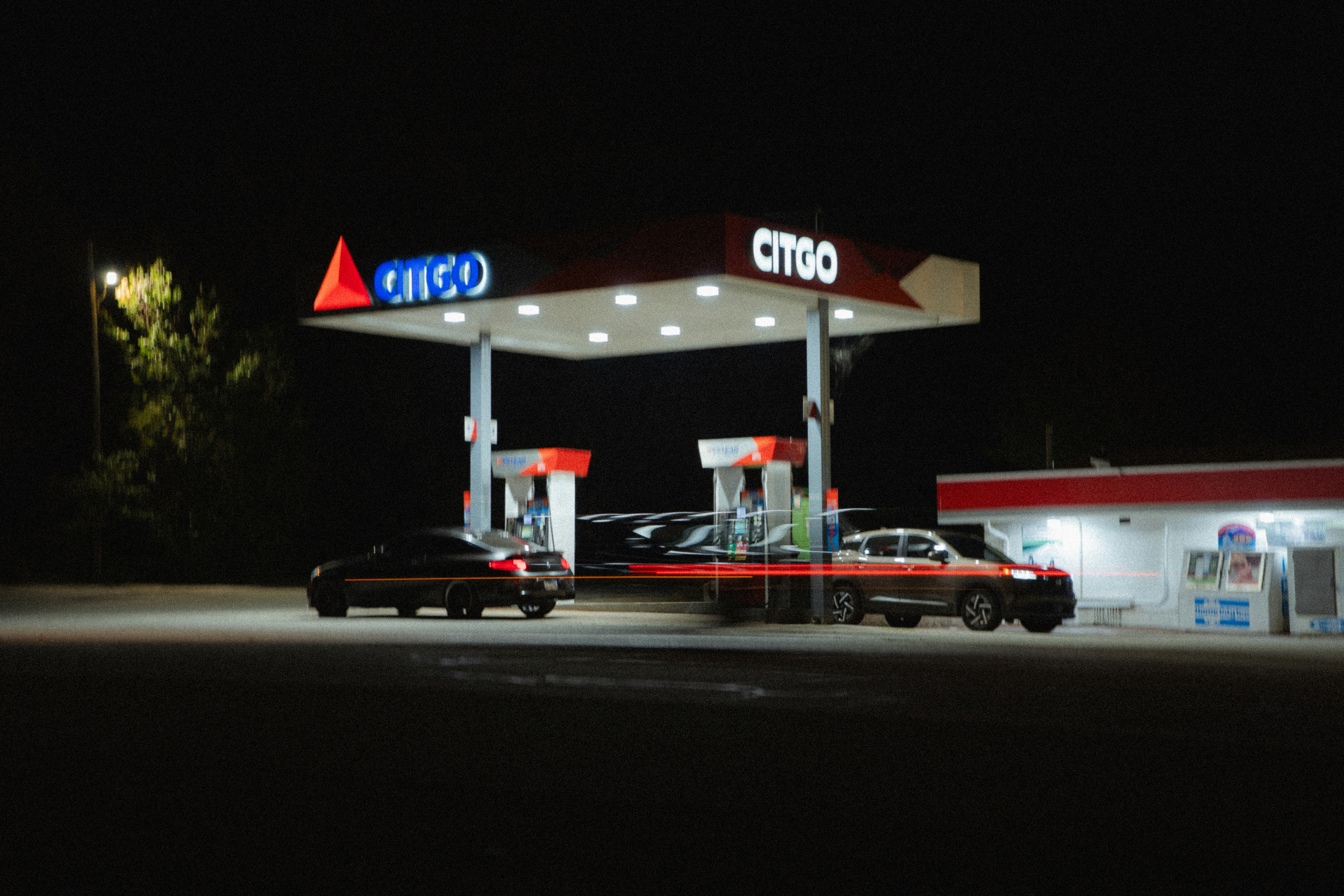 A Citgo gas station at night with cars parked under the illuminated canopy