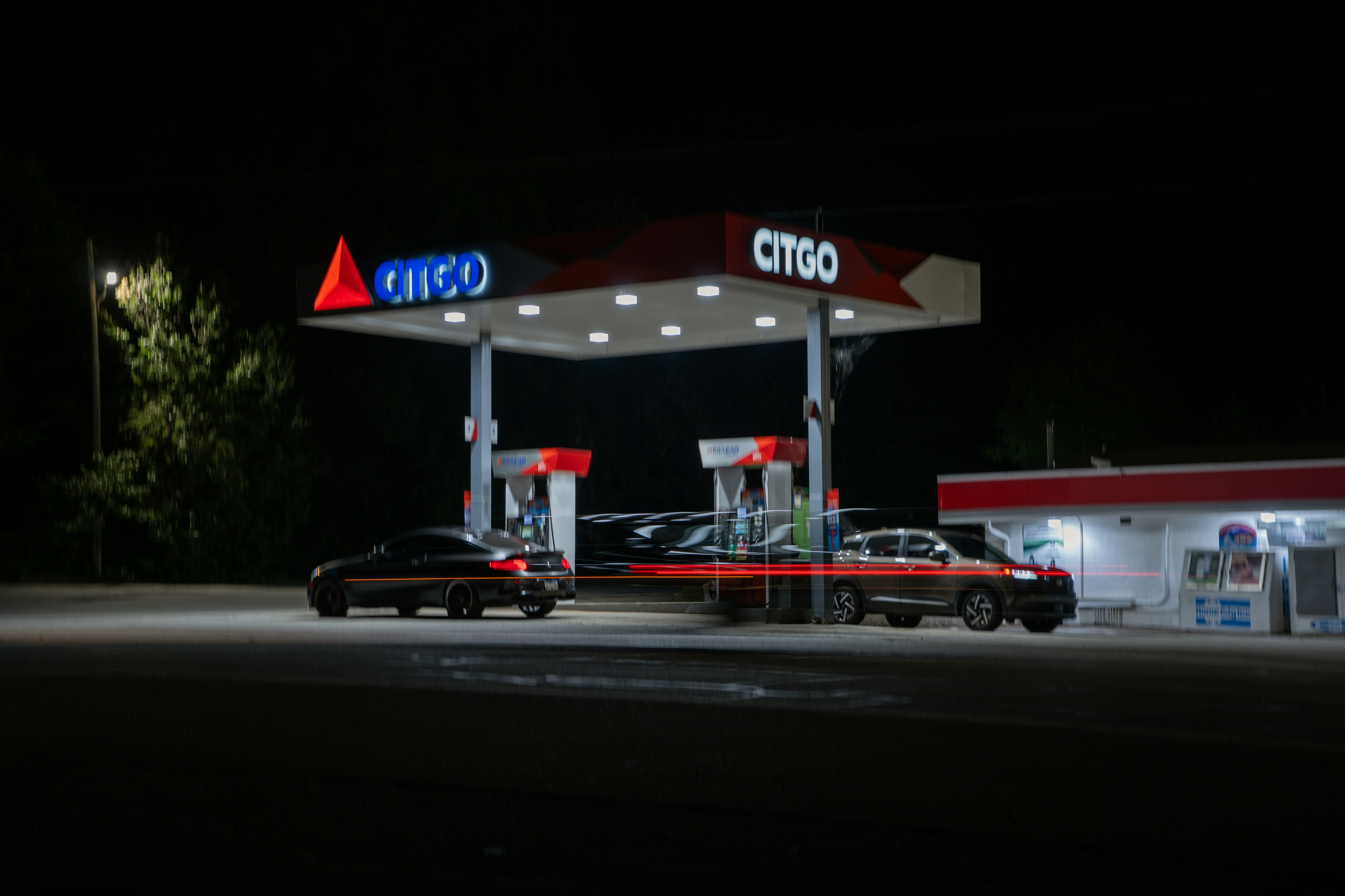 Cars parked at a Citgo gas station under bright canopy lights at night