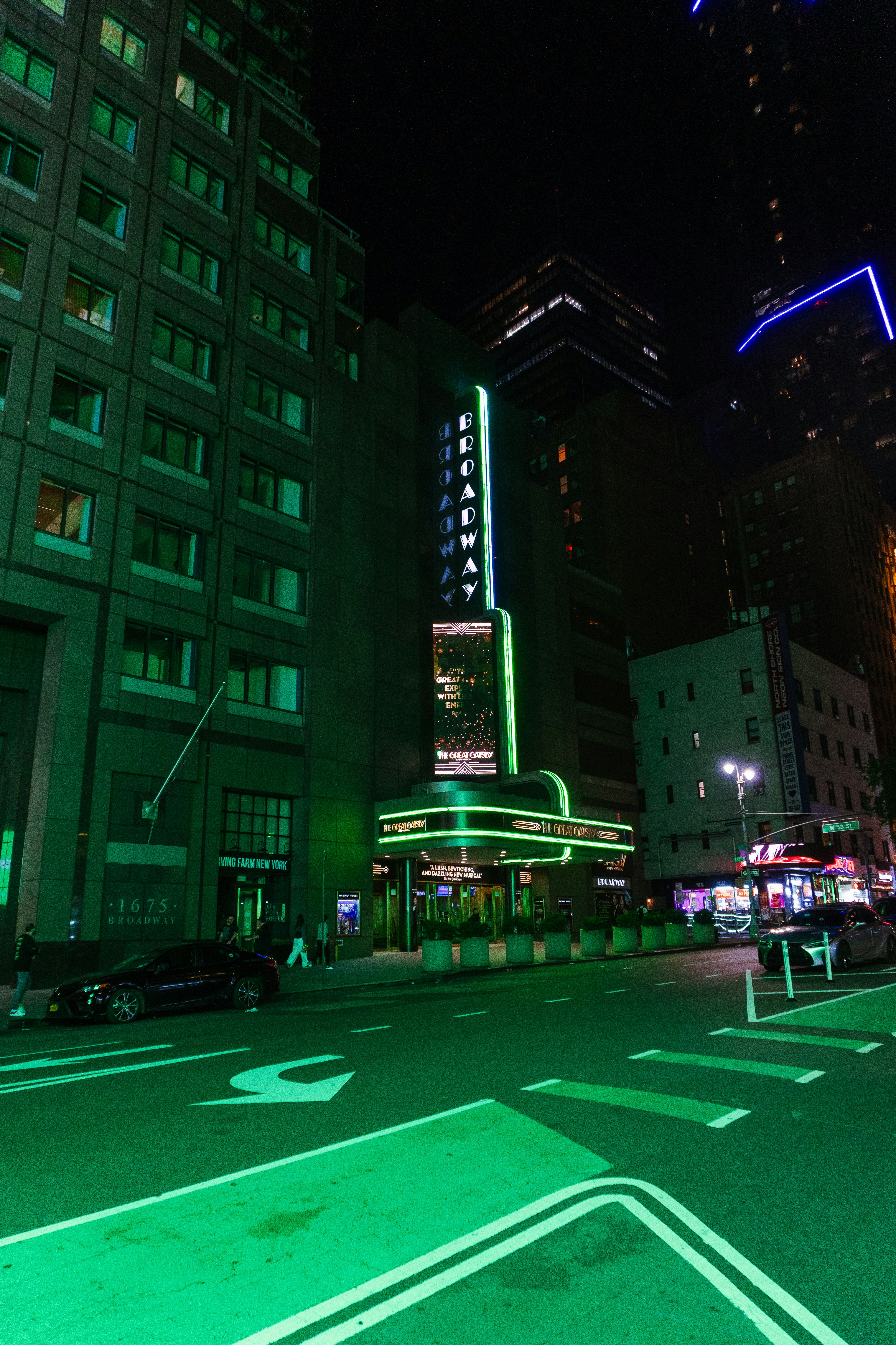 Un chapiteau de théâtre de Broadway illuminé en vert la nuit dans une rue de la ville