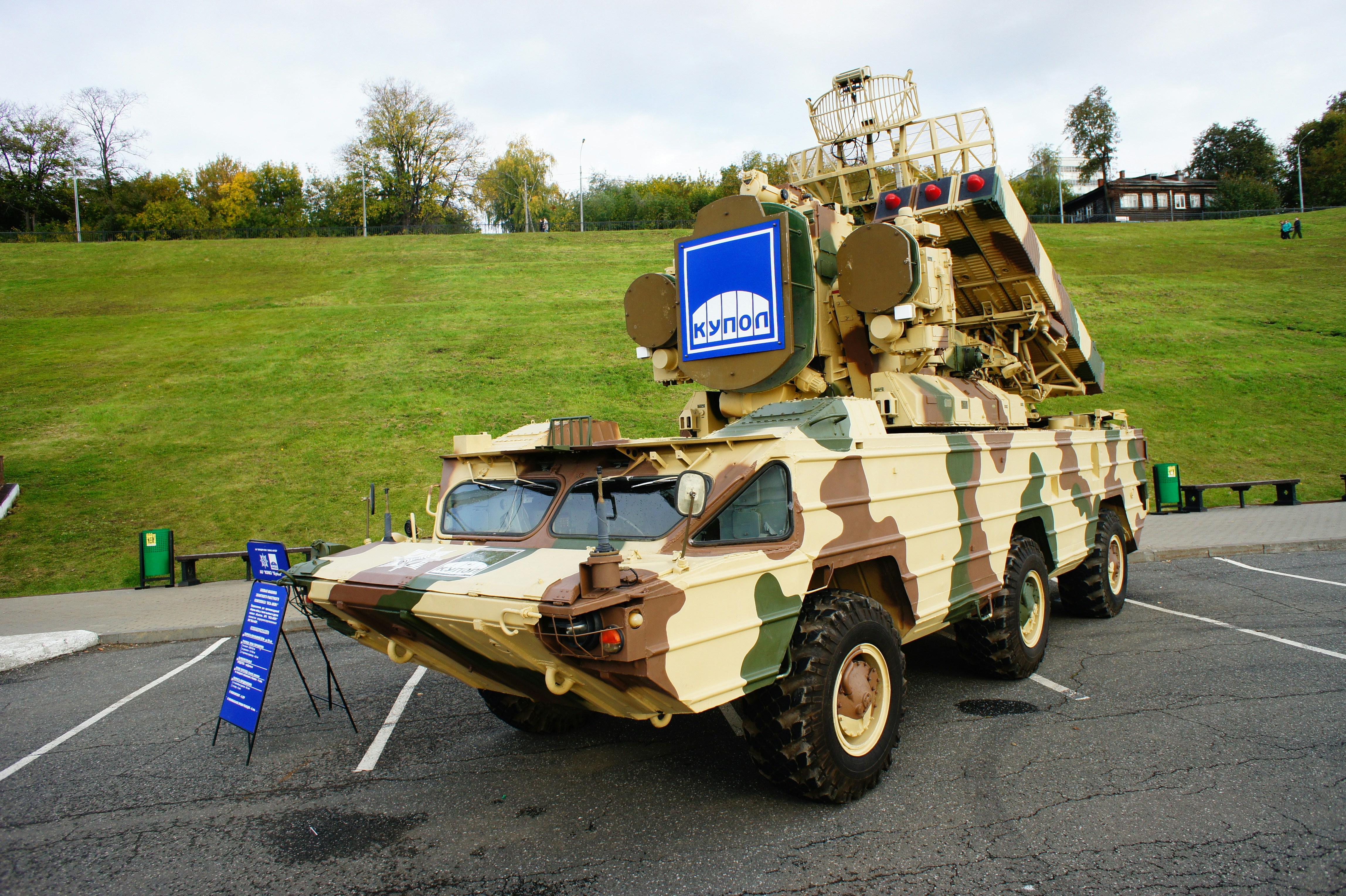 A camouflaged Osa surface-to-air missile system parked on an asphalt lot