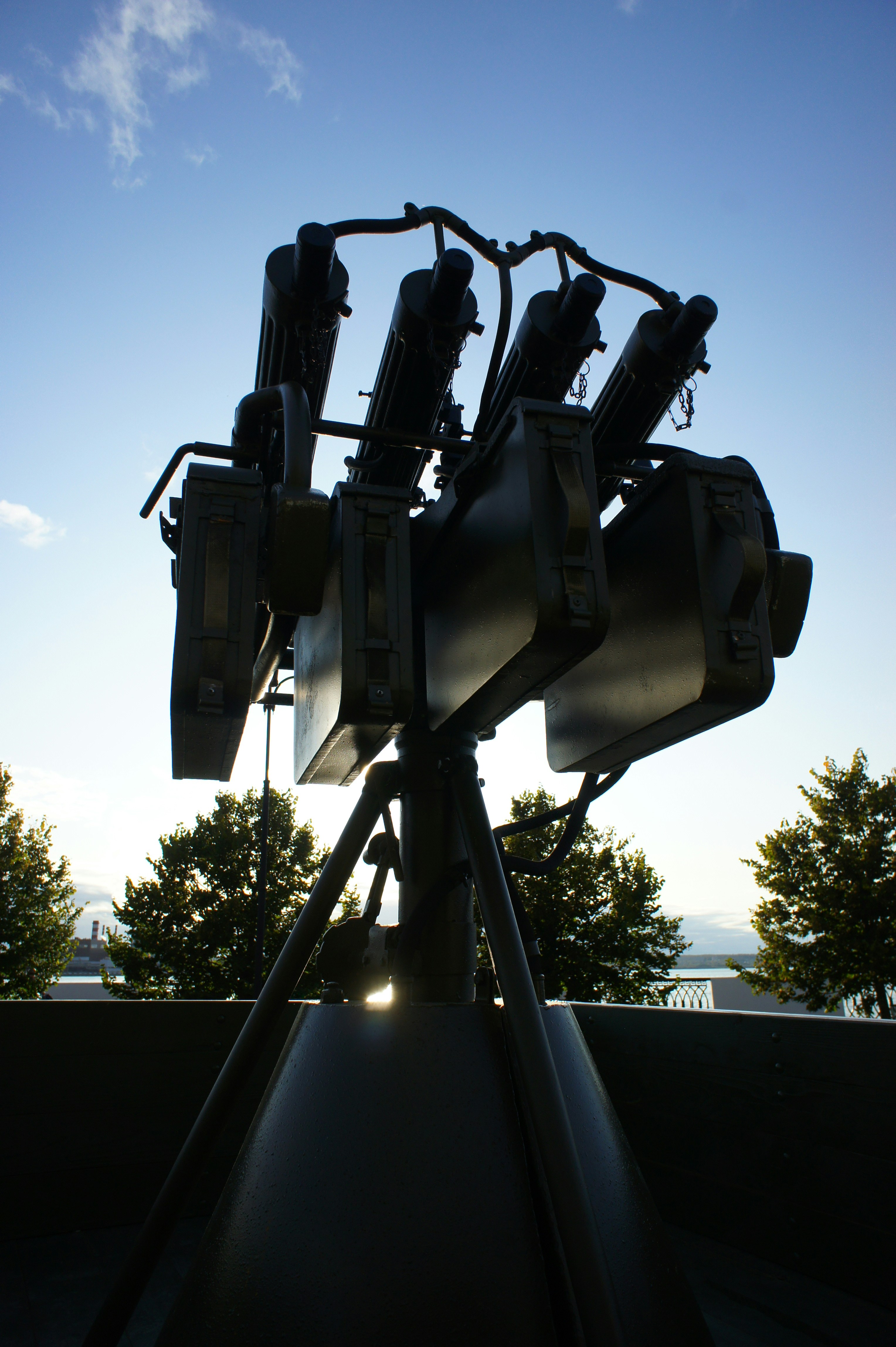 A silhouette of a quadruple anti-aircraft machine gun mount against a blue sky