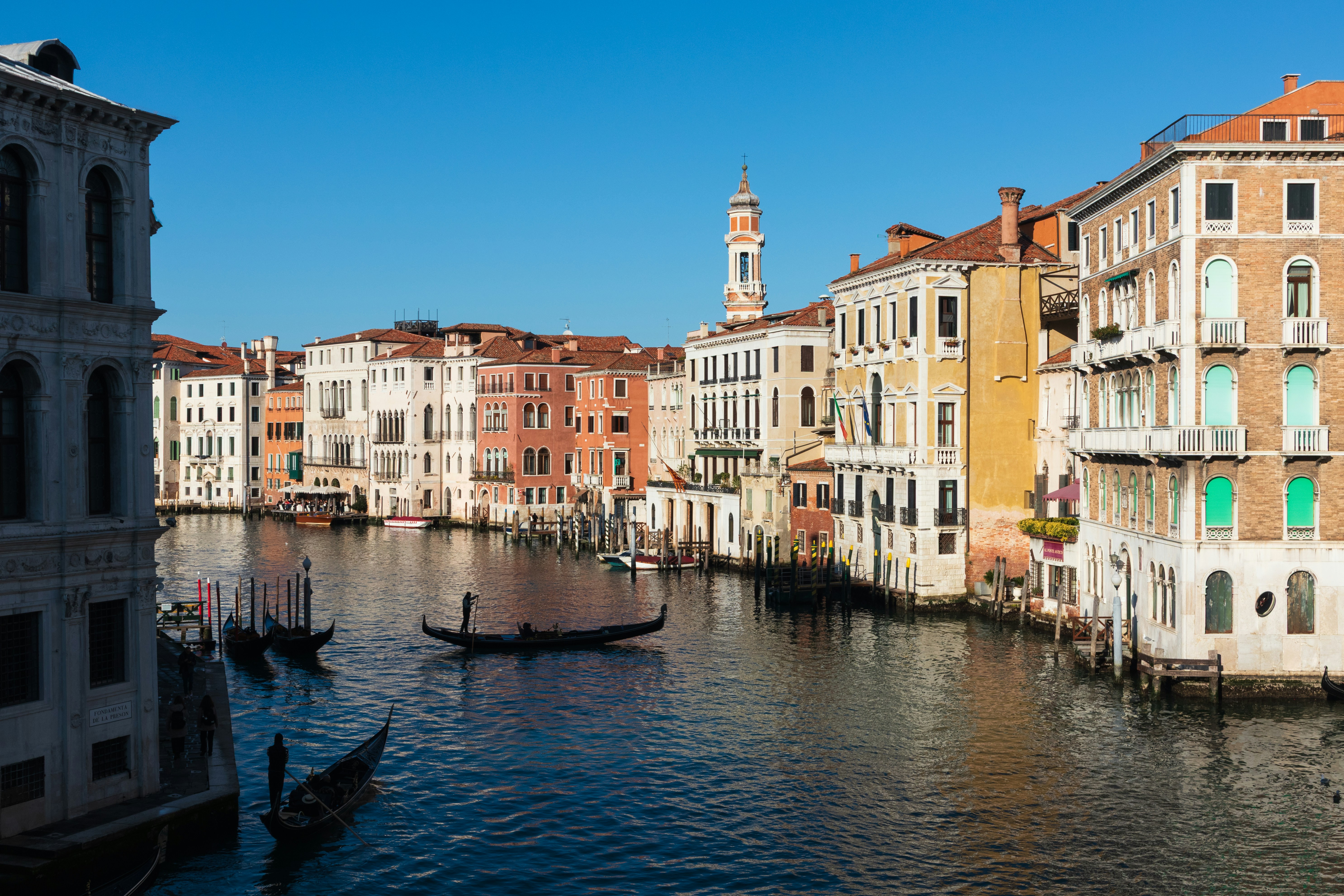 Gondolas on the Grand Canal in Venice with historic buildings under a clear sky