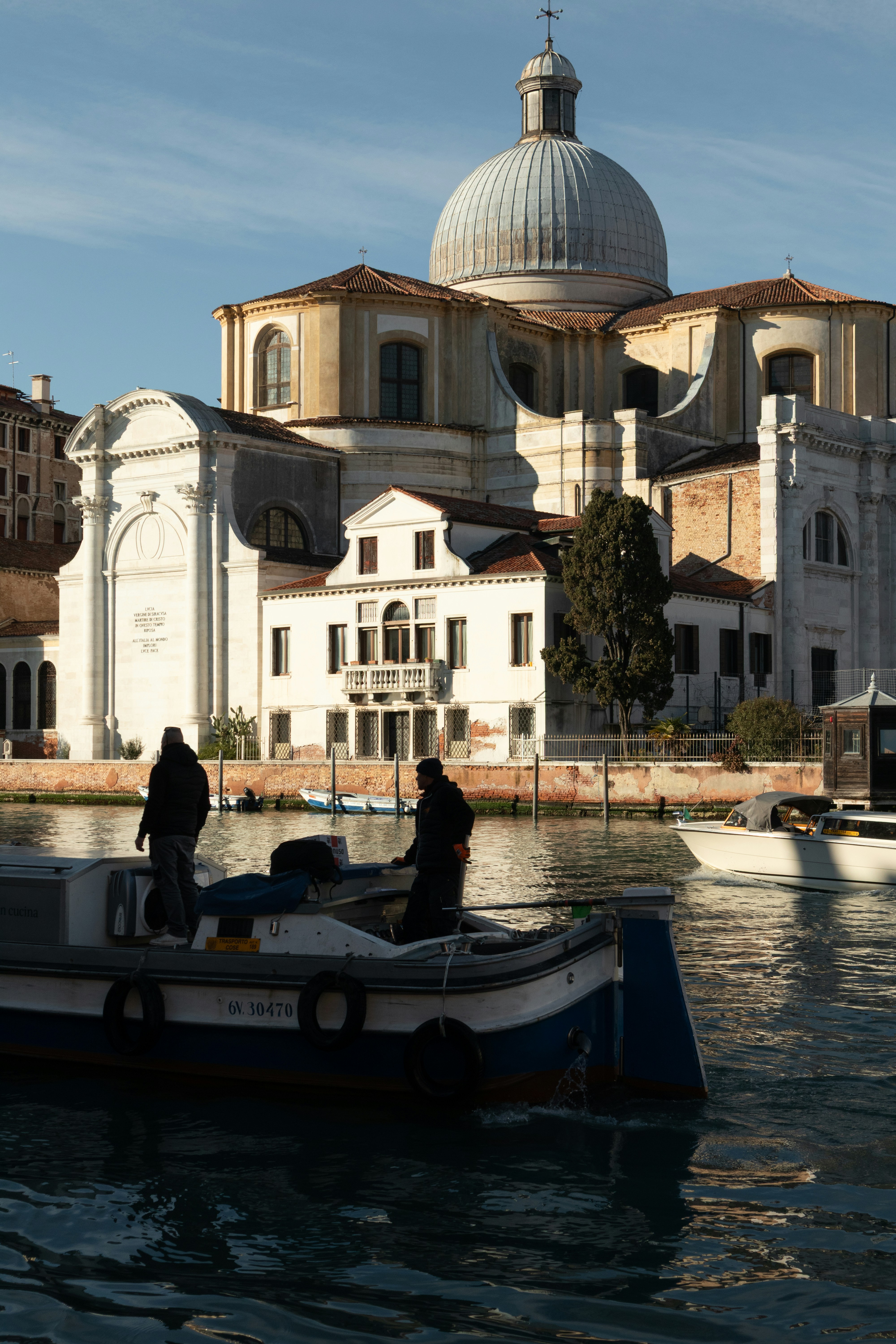 Two people on a work boat on the Grand Canal in Venice, Italy