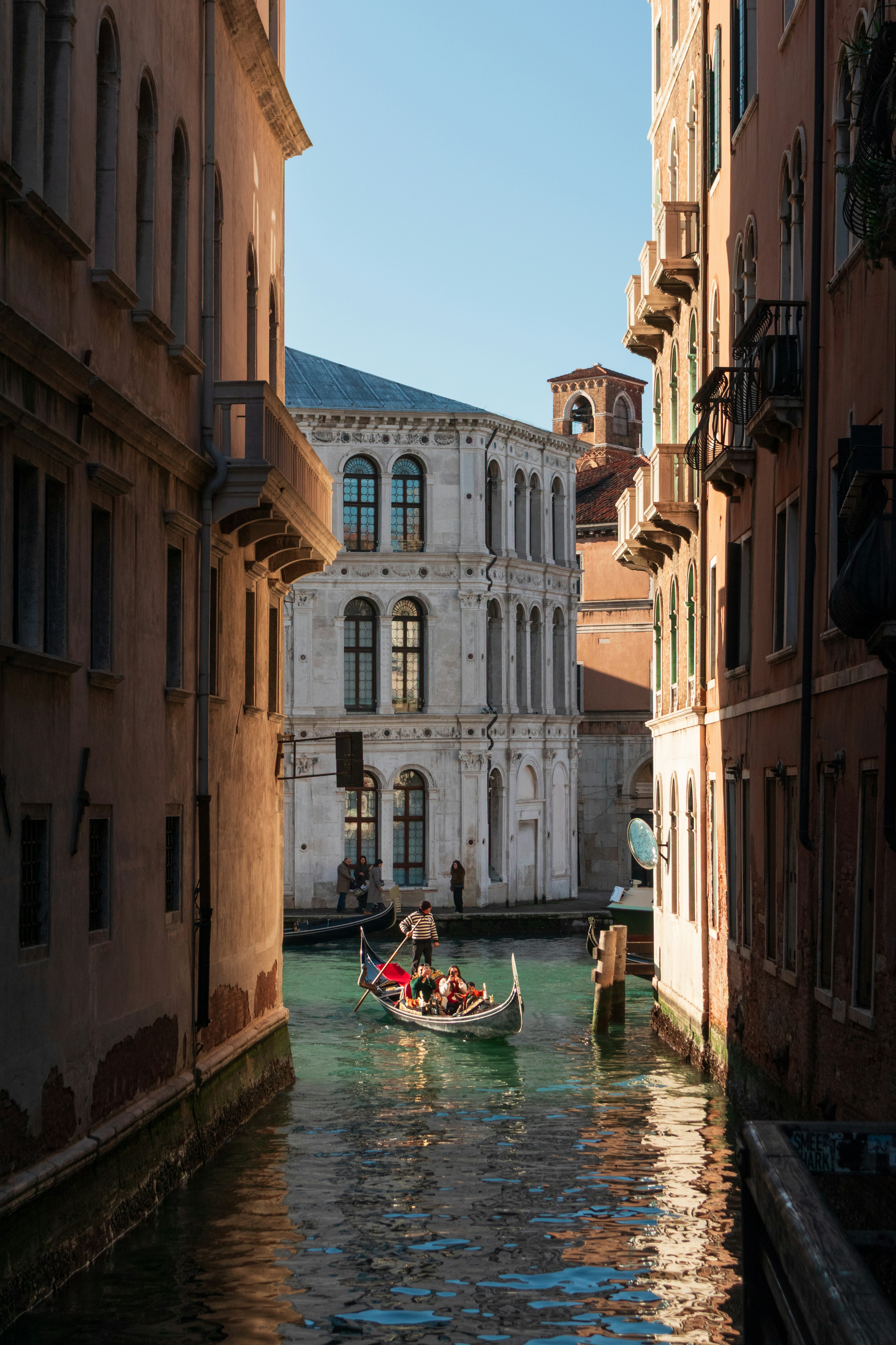 A gondolier rowing a gondola through a narrow canal in Venice, Italy