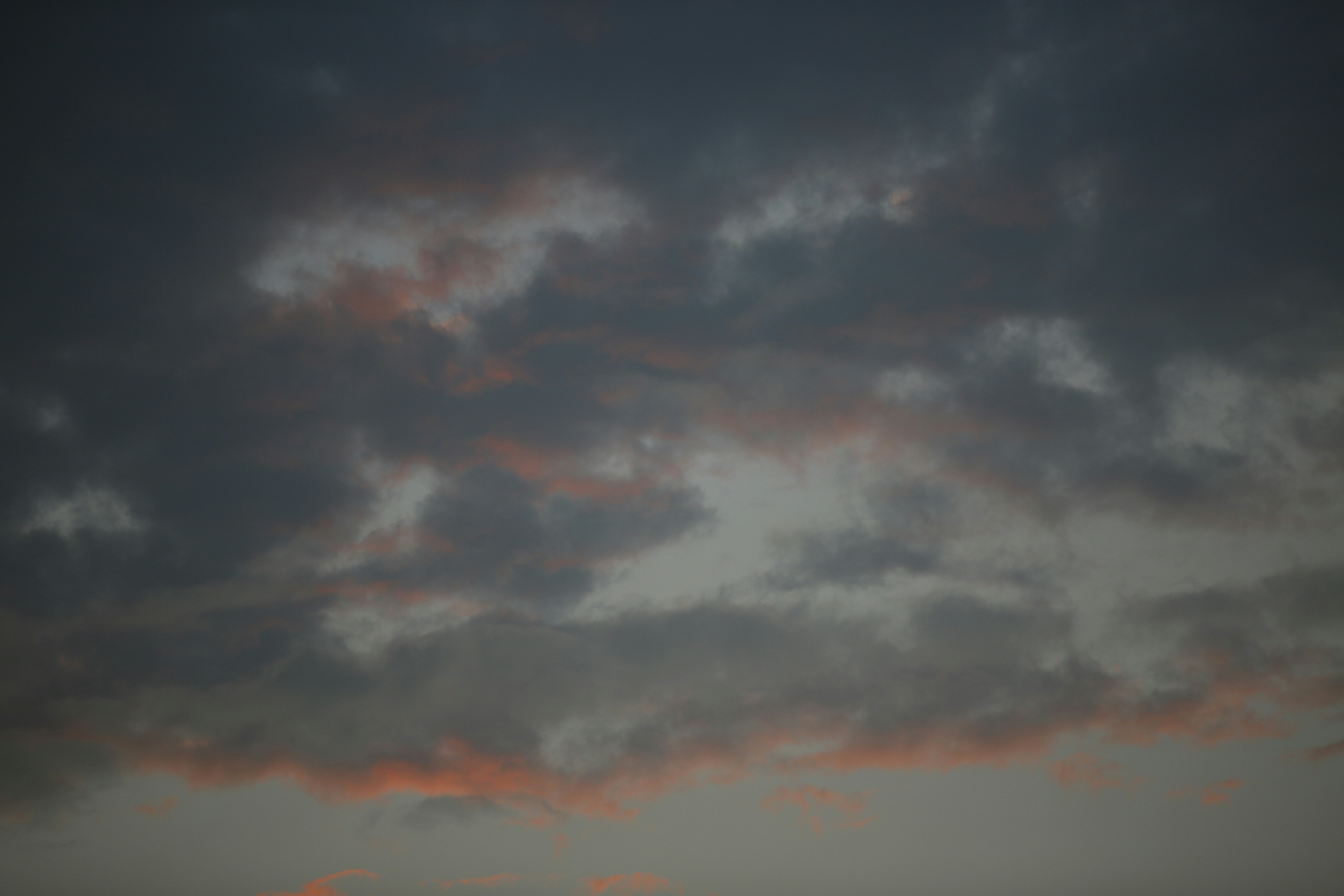 Dark grey clouds with soft orange light along the lower edges